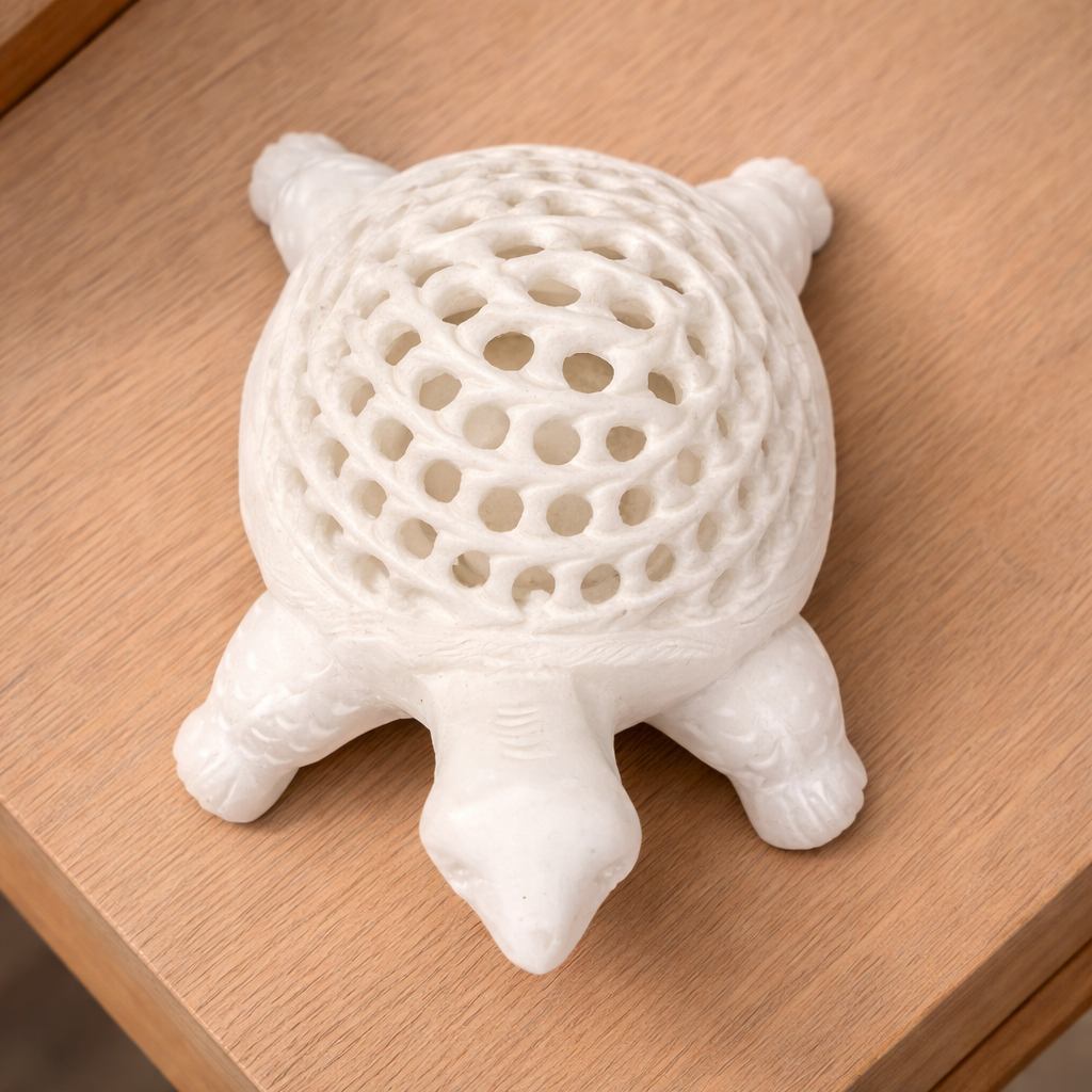 Hand-carved white marble turtle sculpture with lattice shell design placed on wooden table