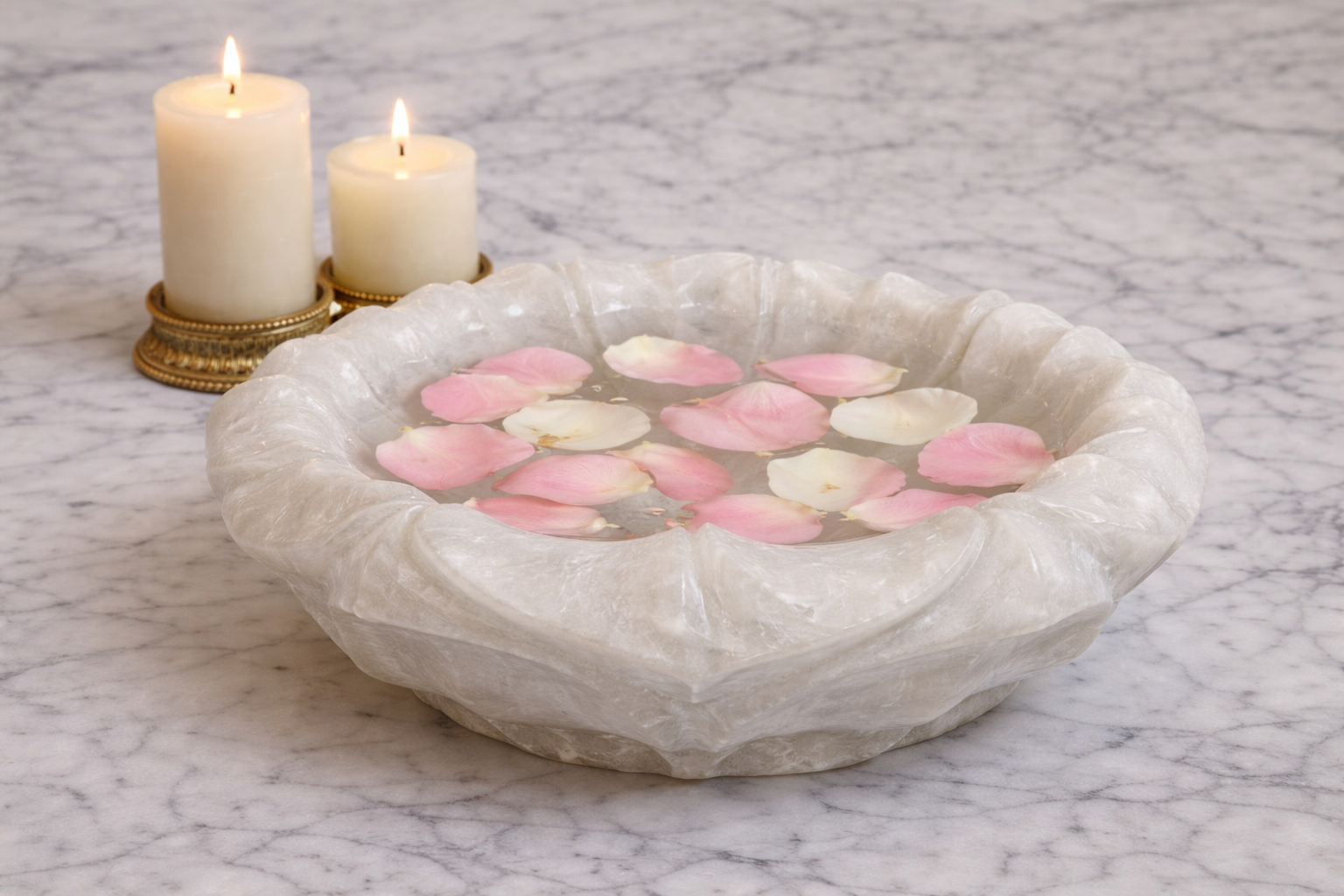 Hand-carved white marble lotus decorative bowl filled with water and floating rose petals beside candles