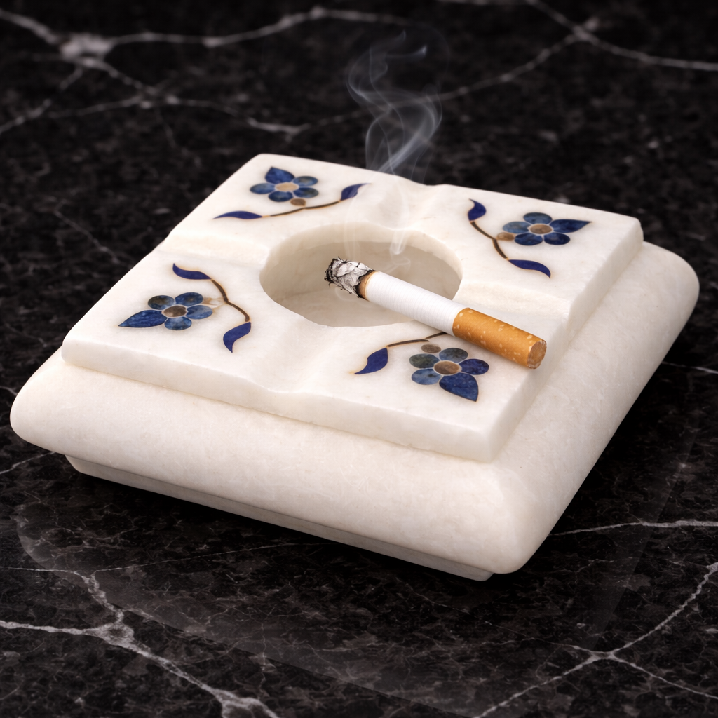 Handcrafted white marble ashtray with blue floral stone inlay on dark marble surface