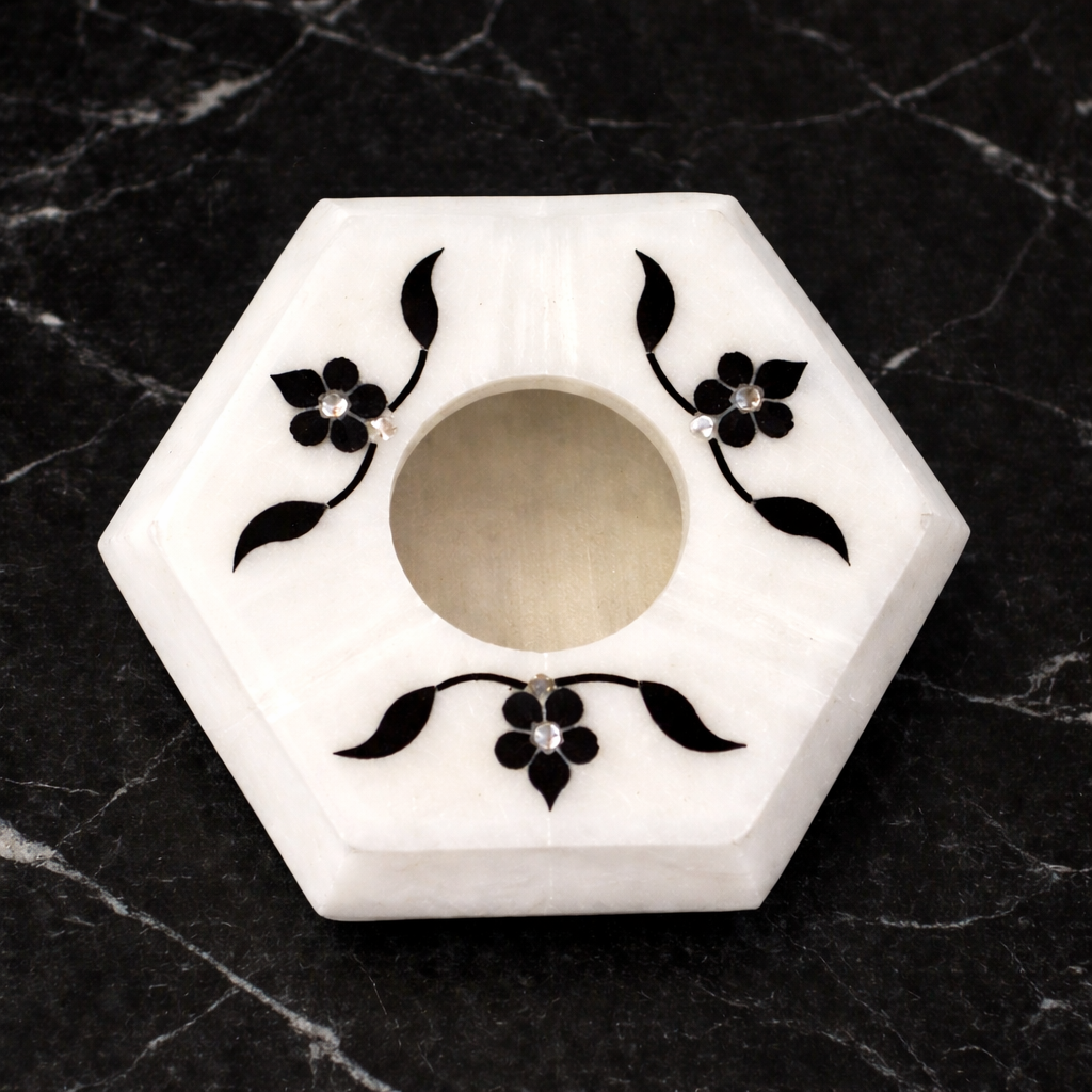 Handcrafted white marble hexagon ashtray with black floral inlay on marble surface