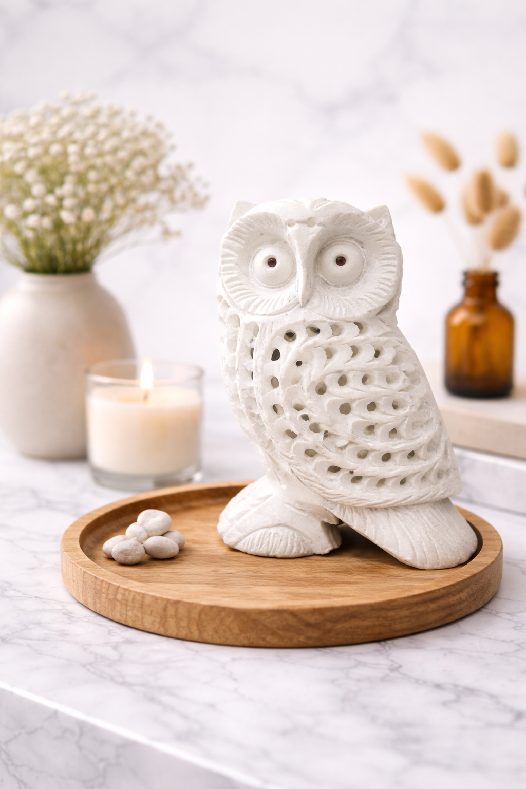 Hand-carved white marble owl sculpture on wooden tray with candle and décor accent