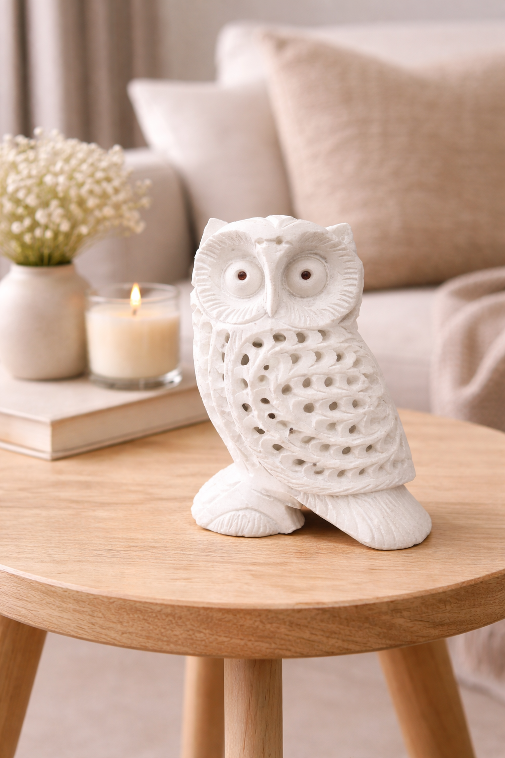 White marble owl figurine with carved feather detailing displayed on round wooden side table in cozy living room setting