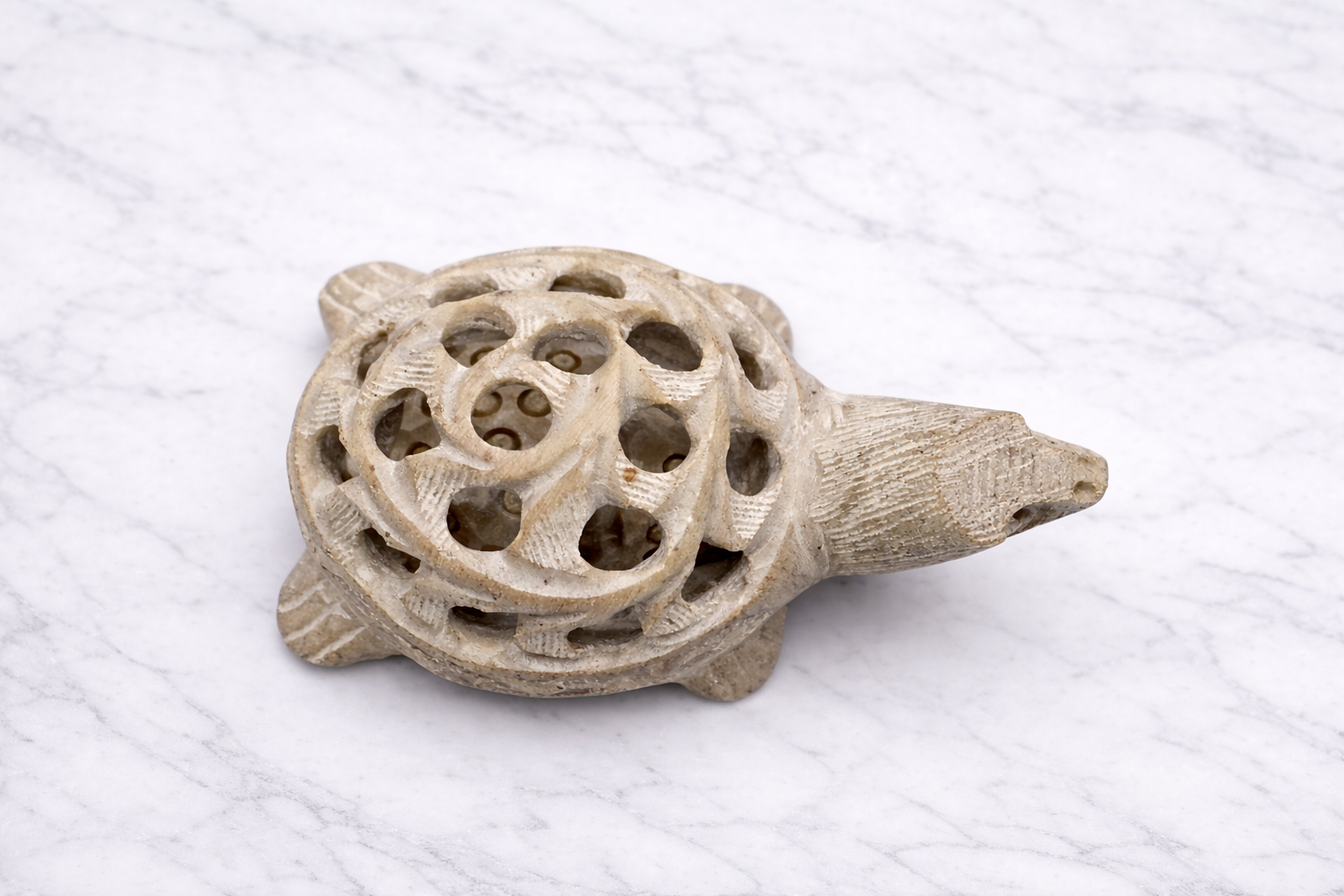 Hand-carved white marble turtle sculpture with intricate lattice shell design on marble surface
