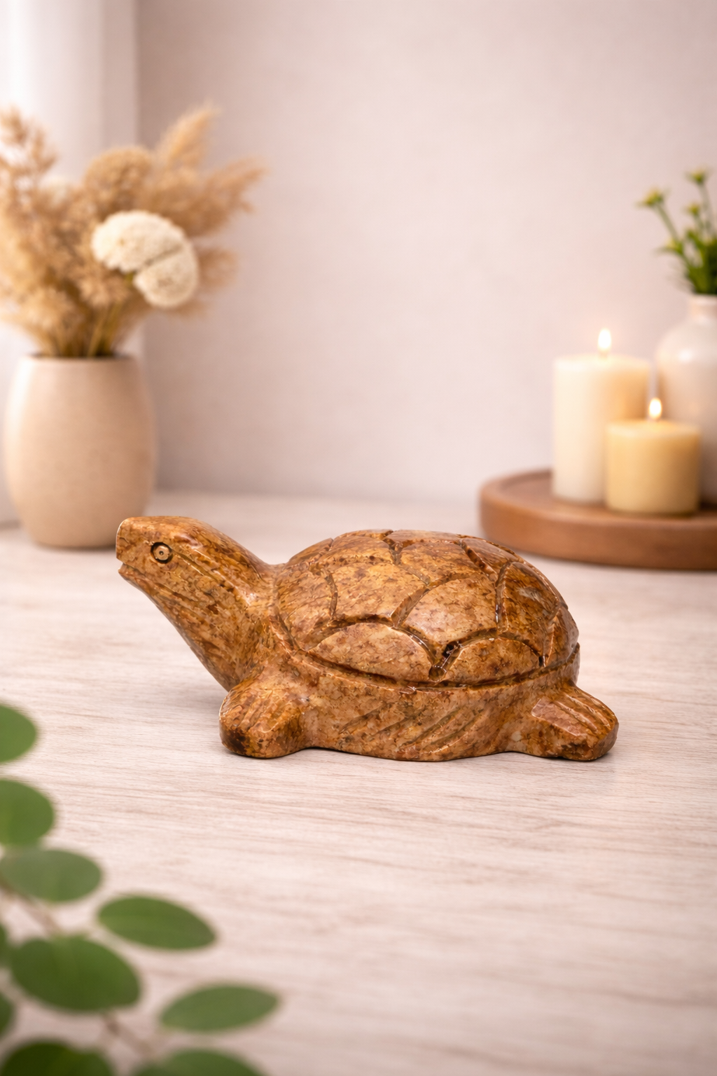 Hand-carved polished soapstone turtle sculpture styled on tabletop with candles in background