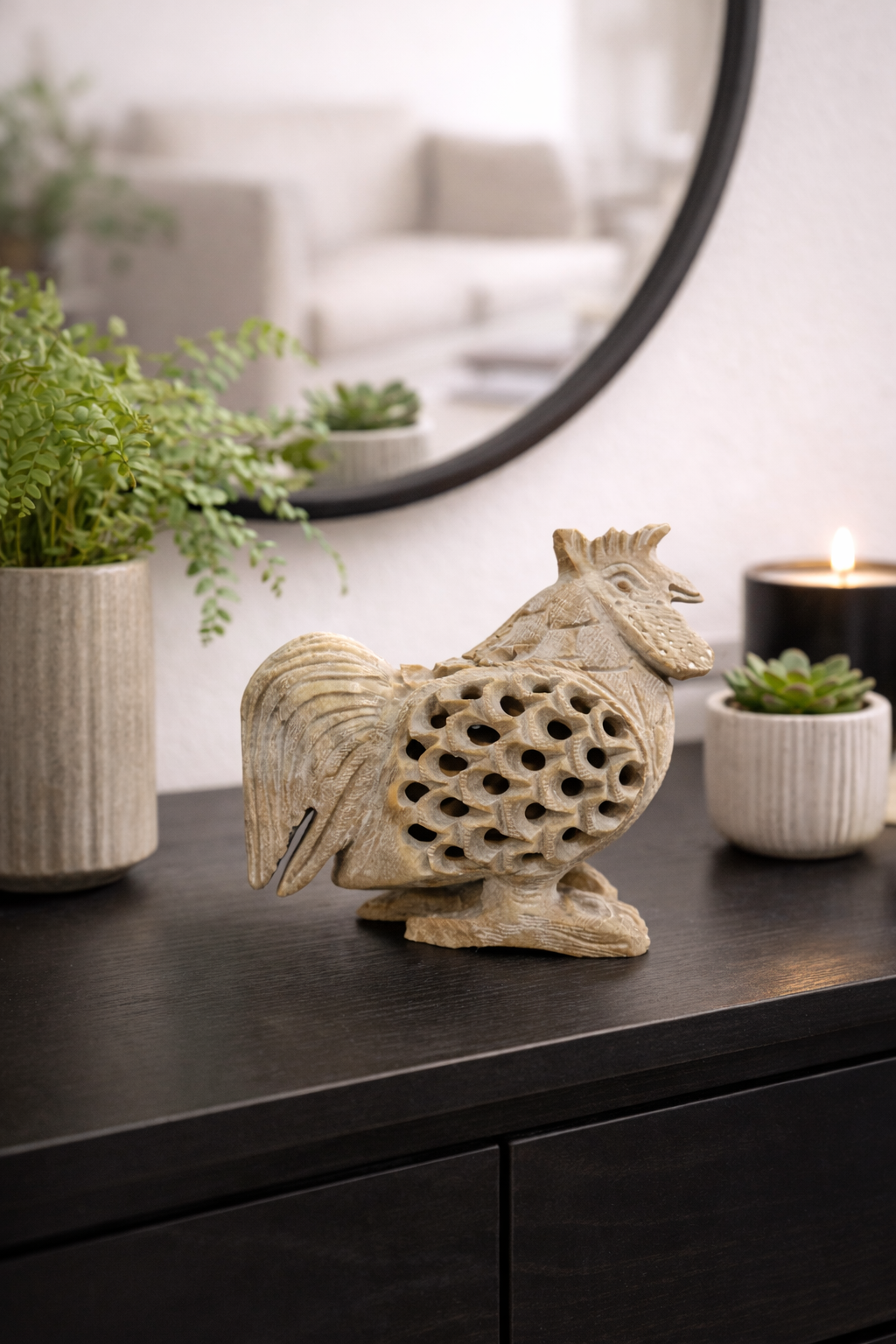 Hand-carved soapstone rooster sculpture styled on dark console table with plants and mirror