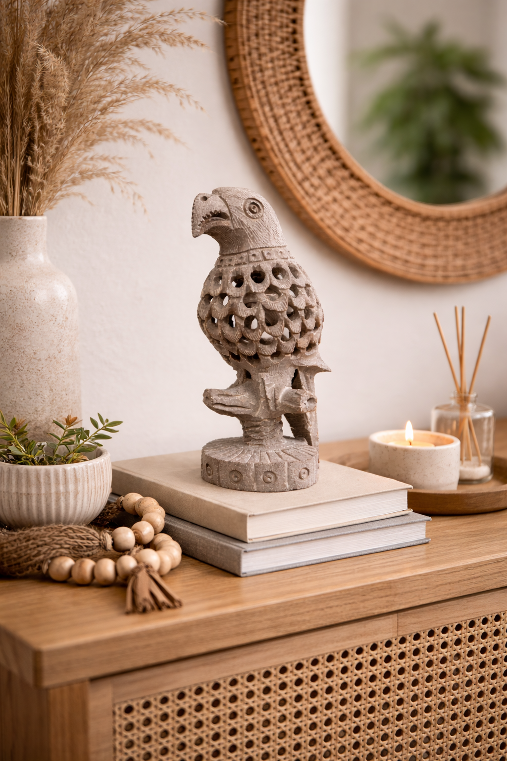 Hand-carved soapstone parrot sculpture styled on books with candle and woven mirror in modern home setting