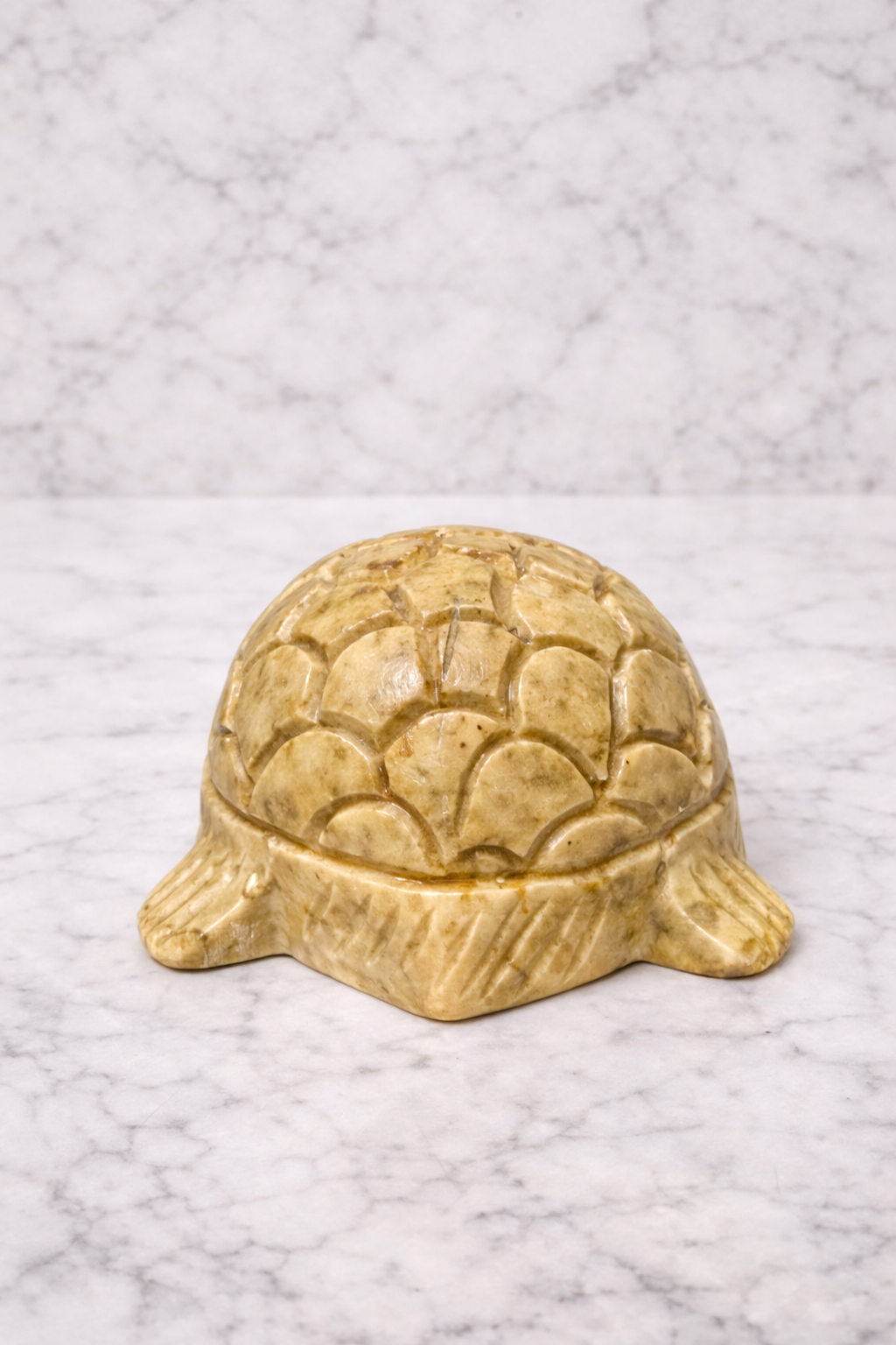 Rare view of Hand-carved soapstone turtle figurine in warm natural tones on marble background