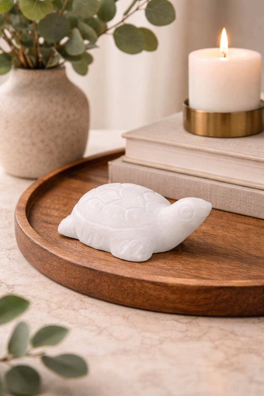 White marble mini turtle figurine styled on wooden tray with candle and books in neutral home setting NZ