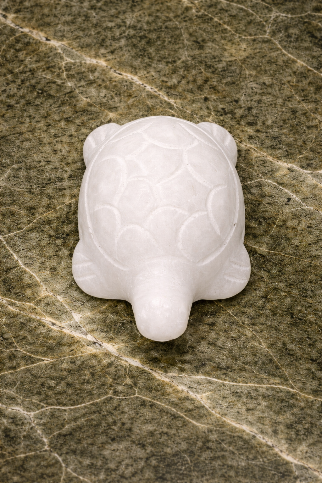 Small white marble turtle sculpture displayed on black marble tabletop