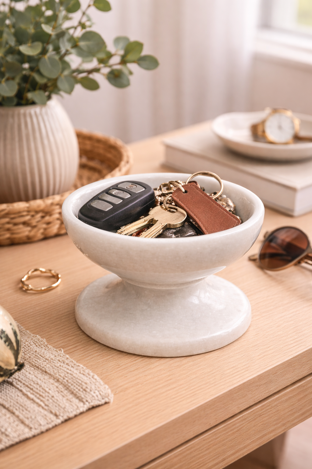White marble pedestal bowl used as entryway key and coin holder on wooden console table