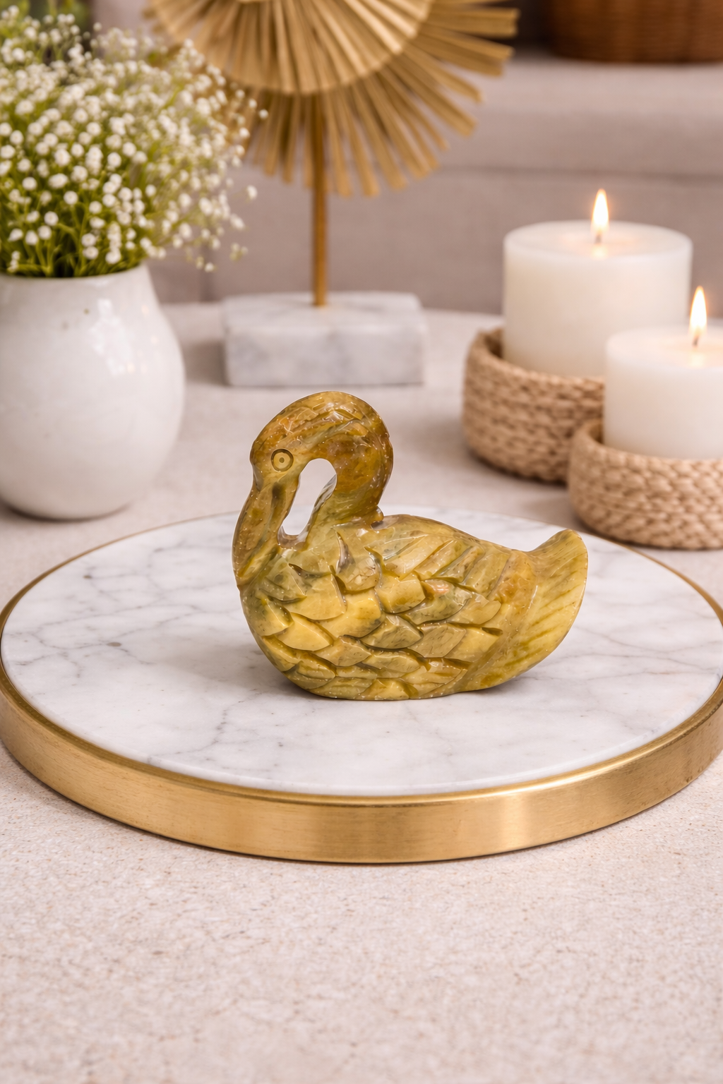 Solid hand-carved soapstone duck figurine with detailed feather carving, natural yellow-green stone finish, displayed on white marble tabletop in modern NZ interior