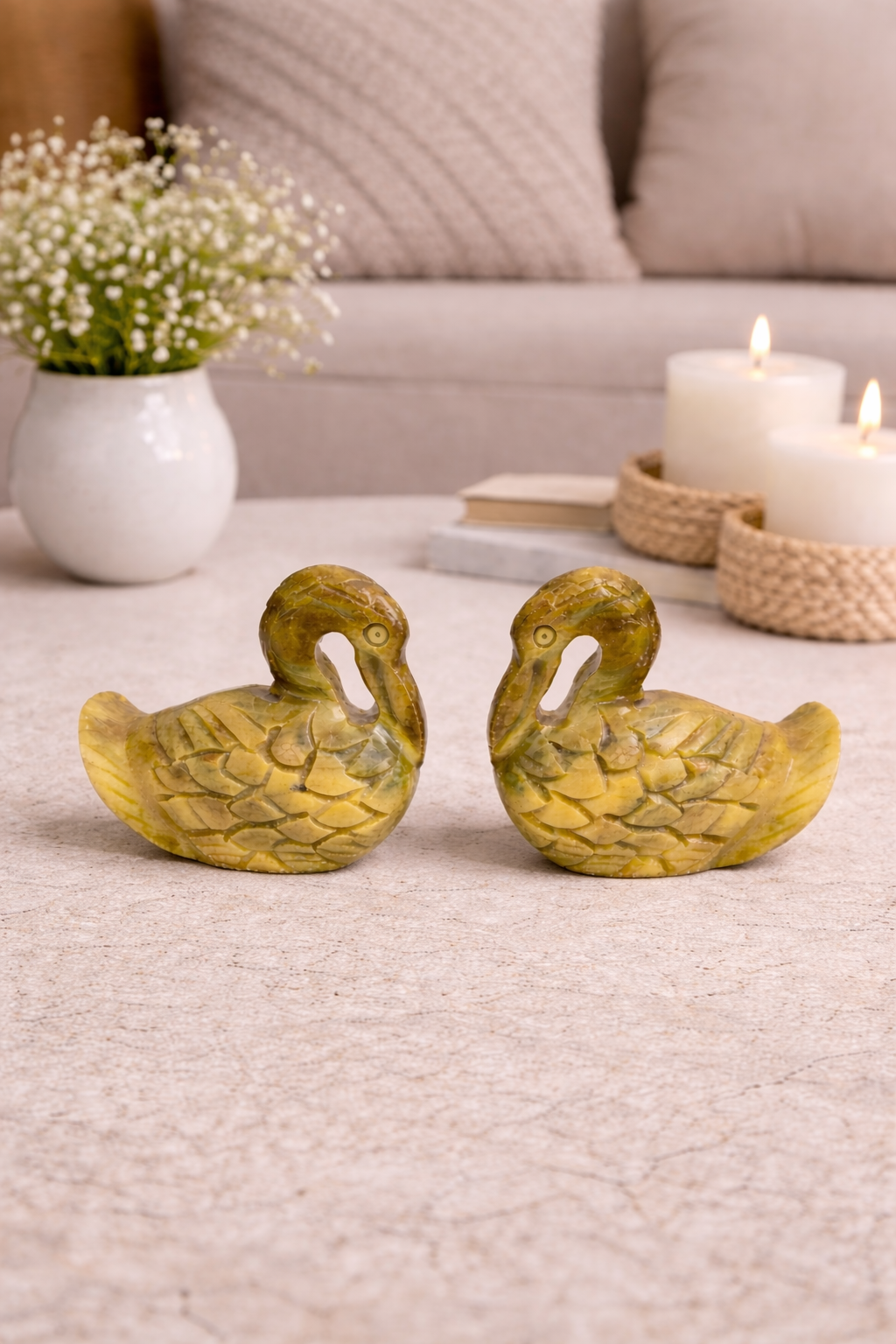 Two polished soapstone duck figurines displayed with candles and flowers in modern neutral home setting NZ