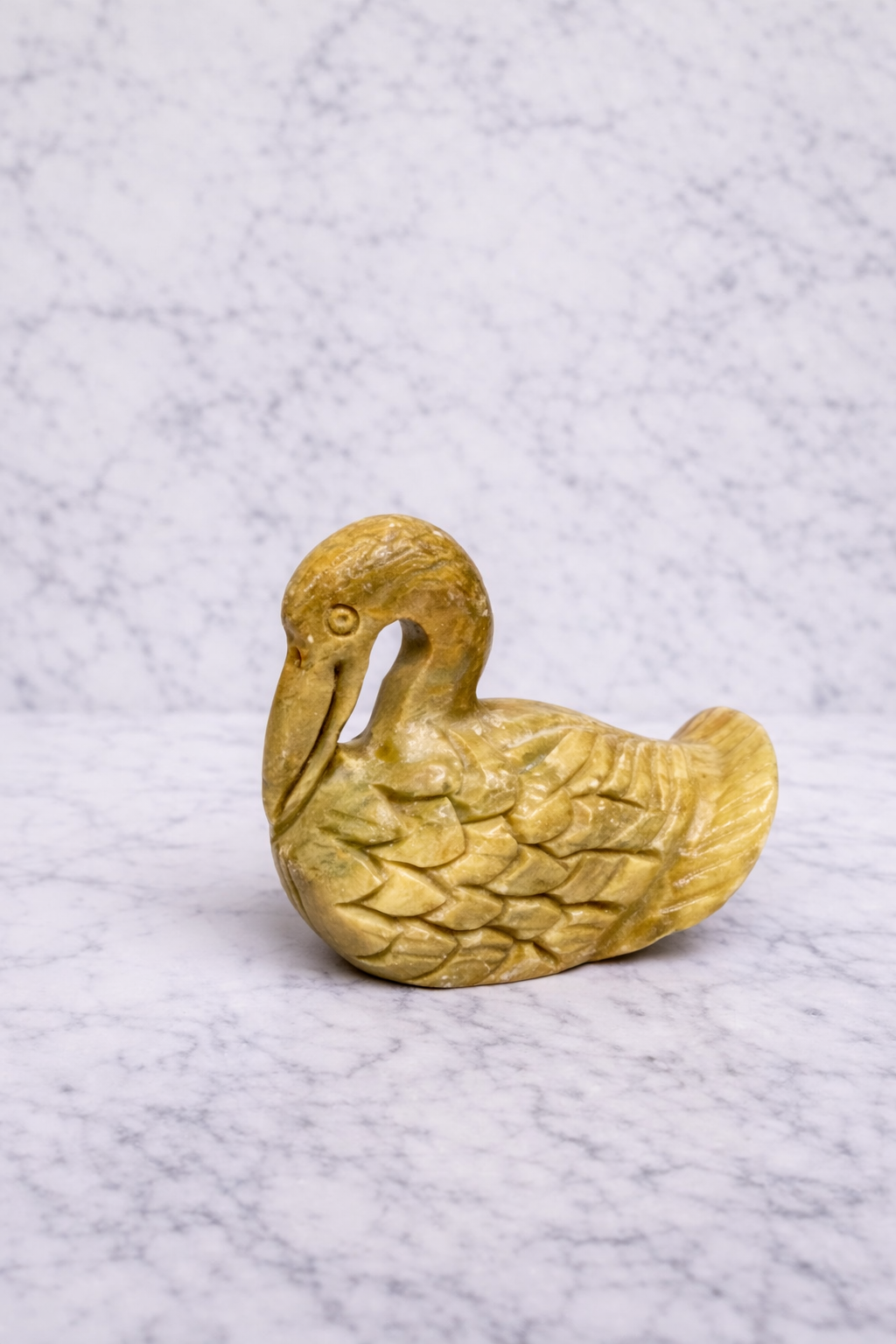 0.152 kg Hand-carved soapstone duck figurine in natural yellow stone on white marble background