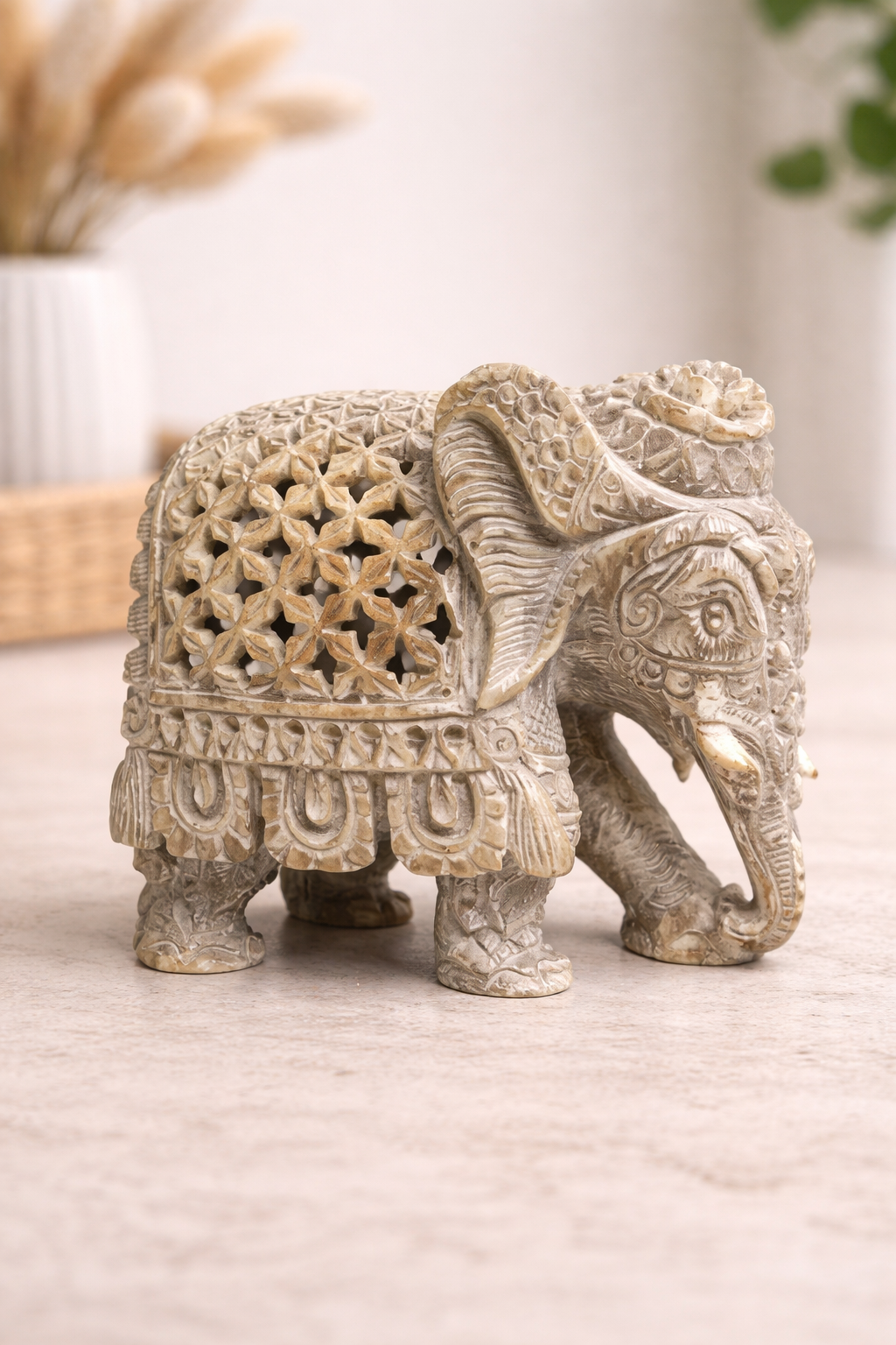 Hand carved soapstone elephant sculpture with hidden inner elephant displayed on light interior surface