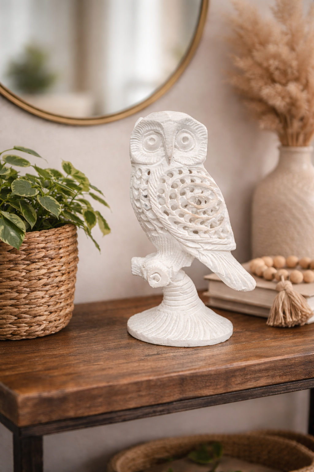 Hand-carved white marble owl sculpture on wooden console table with decorative vase, mirror and indoor plant in living room setting