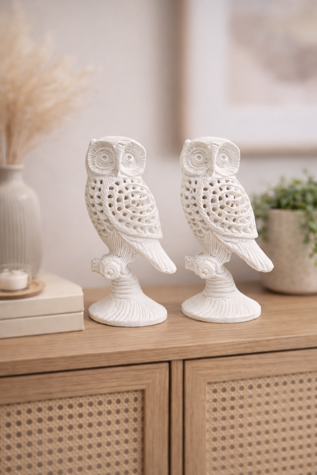 Two hand-carved white marble owl sculptures displayed on a wooden console table