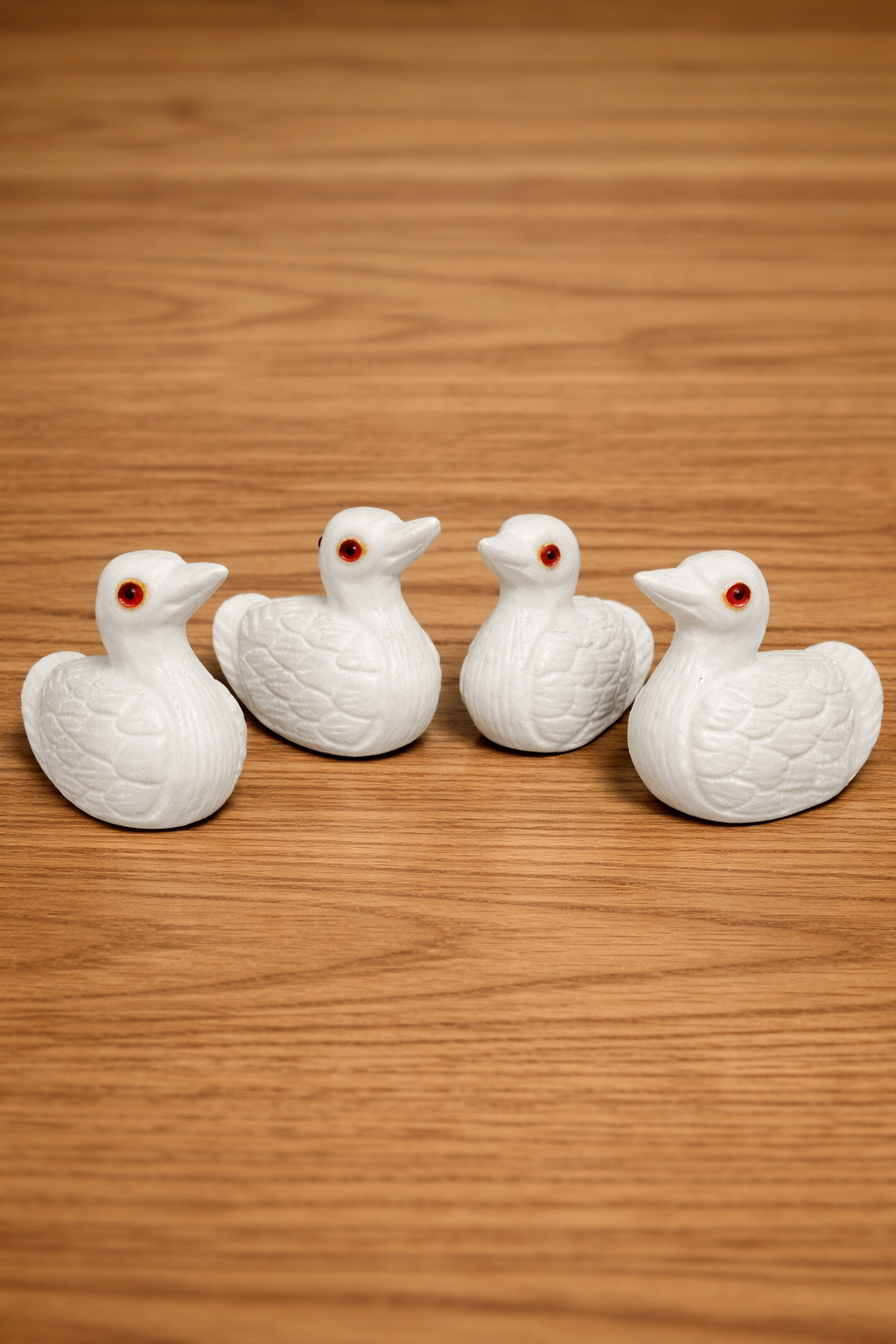 White marble duck figurines with red stone eyes on wooden table, luxury hand-carved stone decor NZ