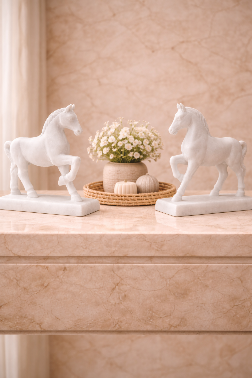 Pair of white marble horse sculptures on stands displayed on marble console table with floral décor