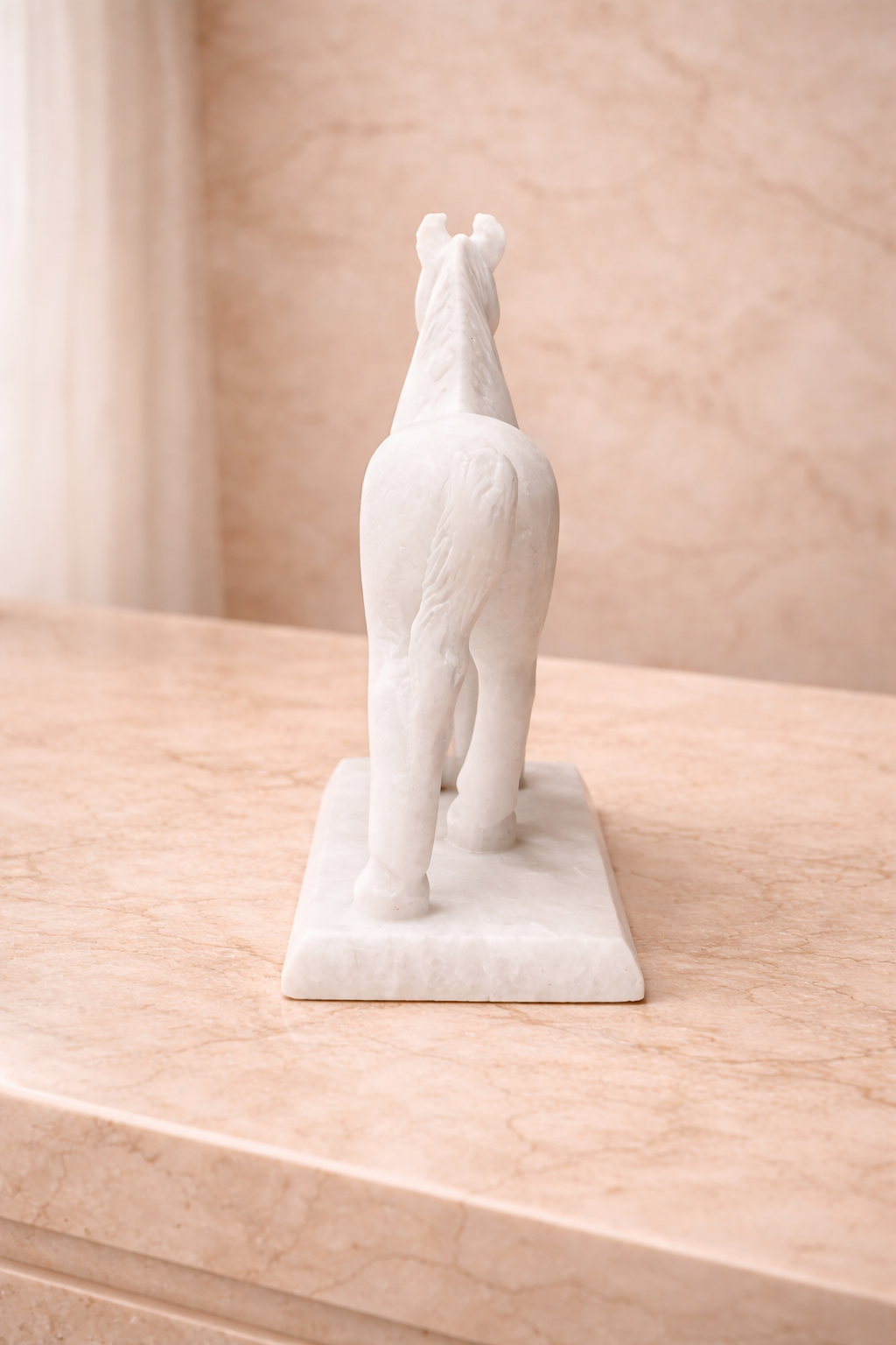 Rear view of white marble horse sculpture on stand displayed on marble console table