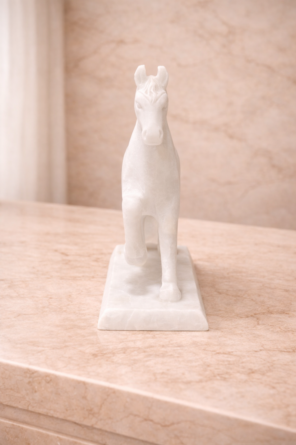 Front view of white marble horse sculpture on stand displayed on marble console table