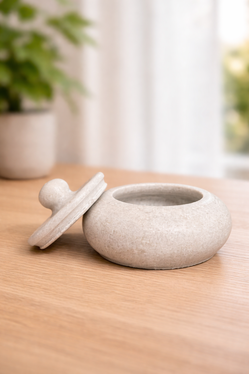 Handcrafted white marble bowl with lid displayed on wooden table