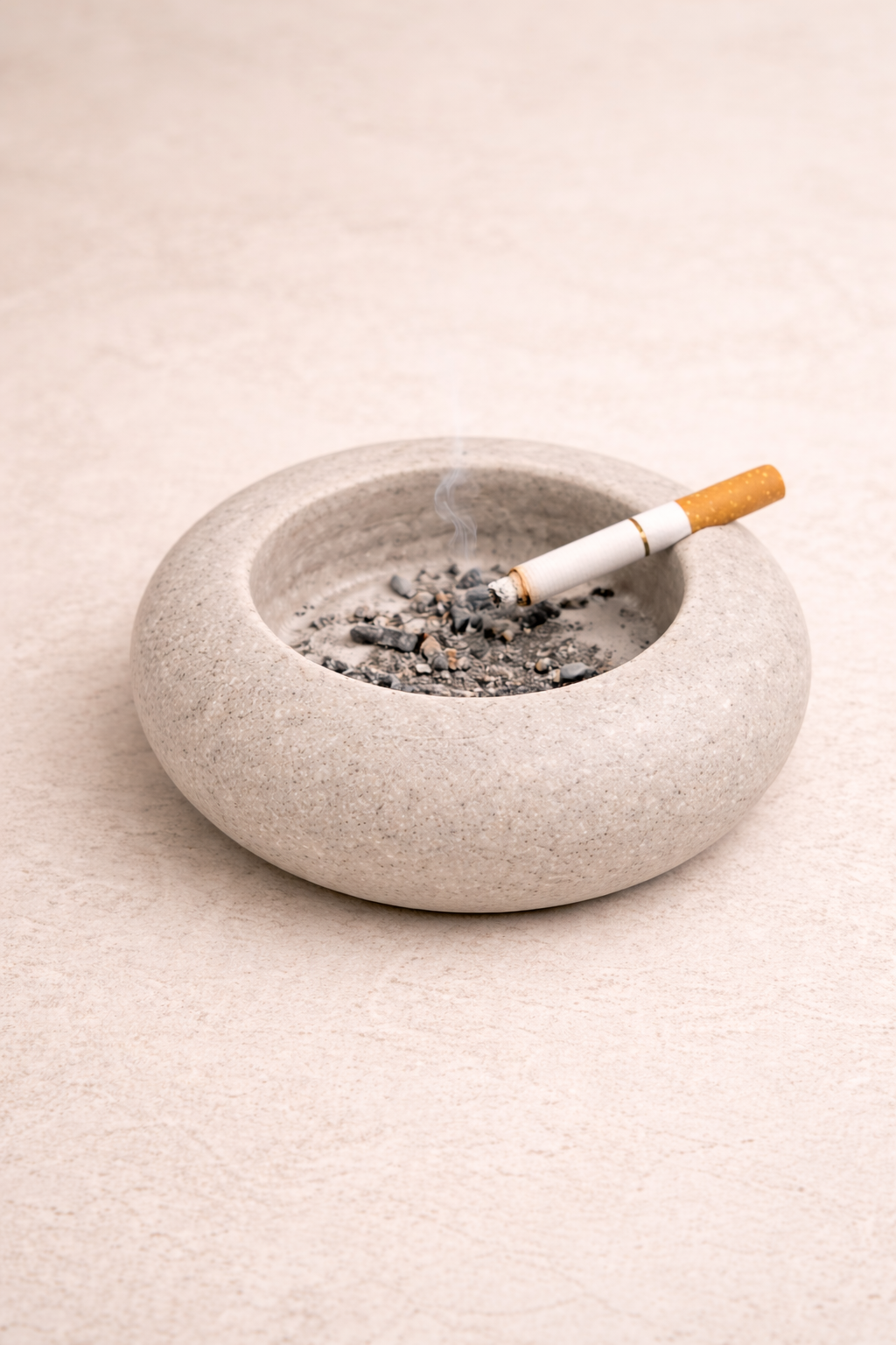 Small white marble bowl used as minimalist stone ashtray on wooden surface