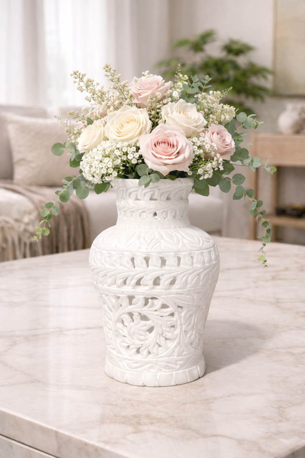 Hand-carved white marble vase with pink and white roses styled on dark wooden table