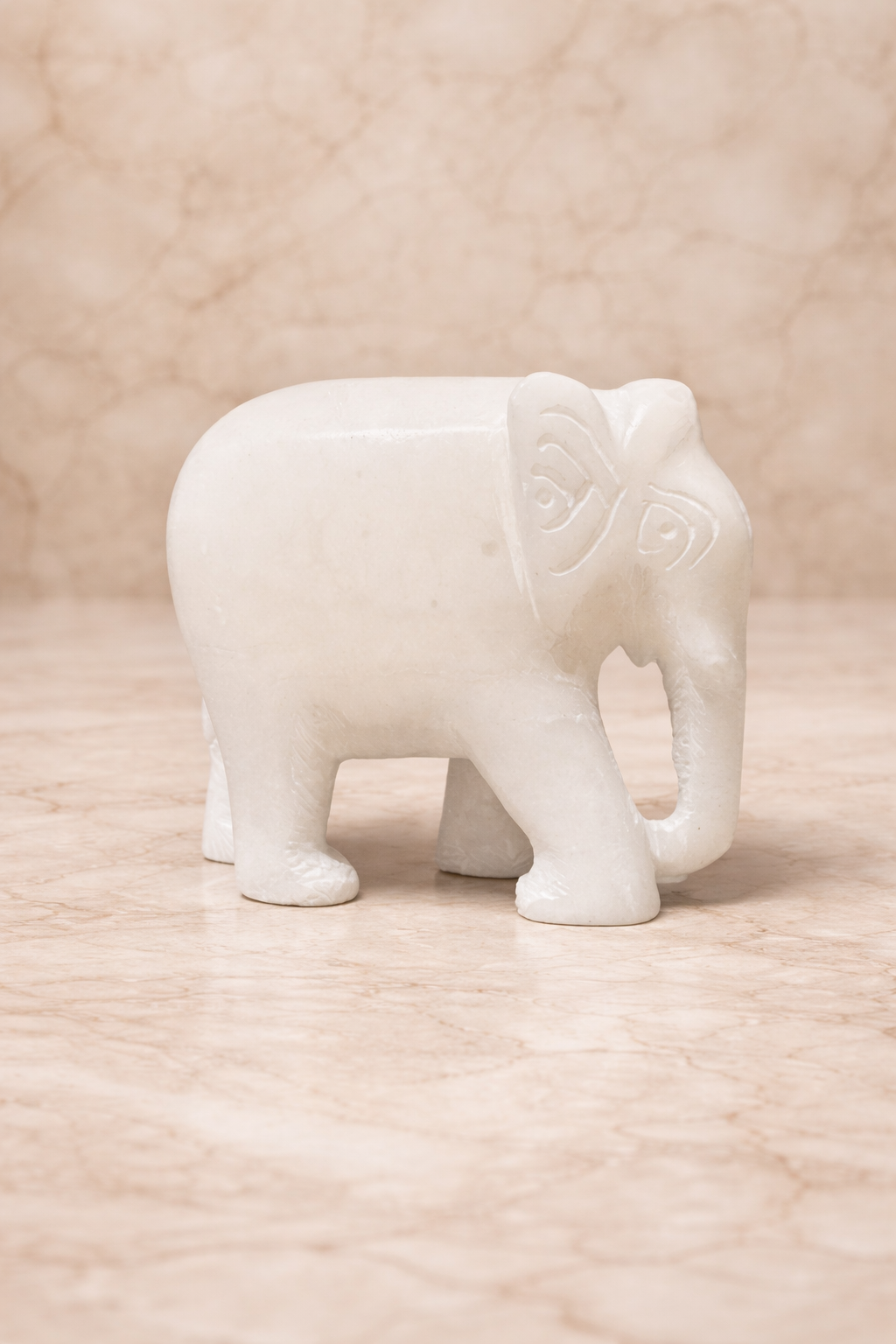White marble elephant figurine close-up on warm beige stone background