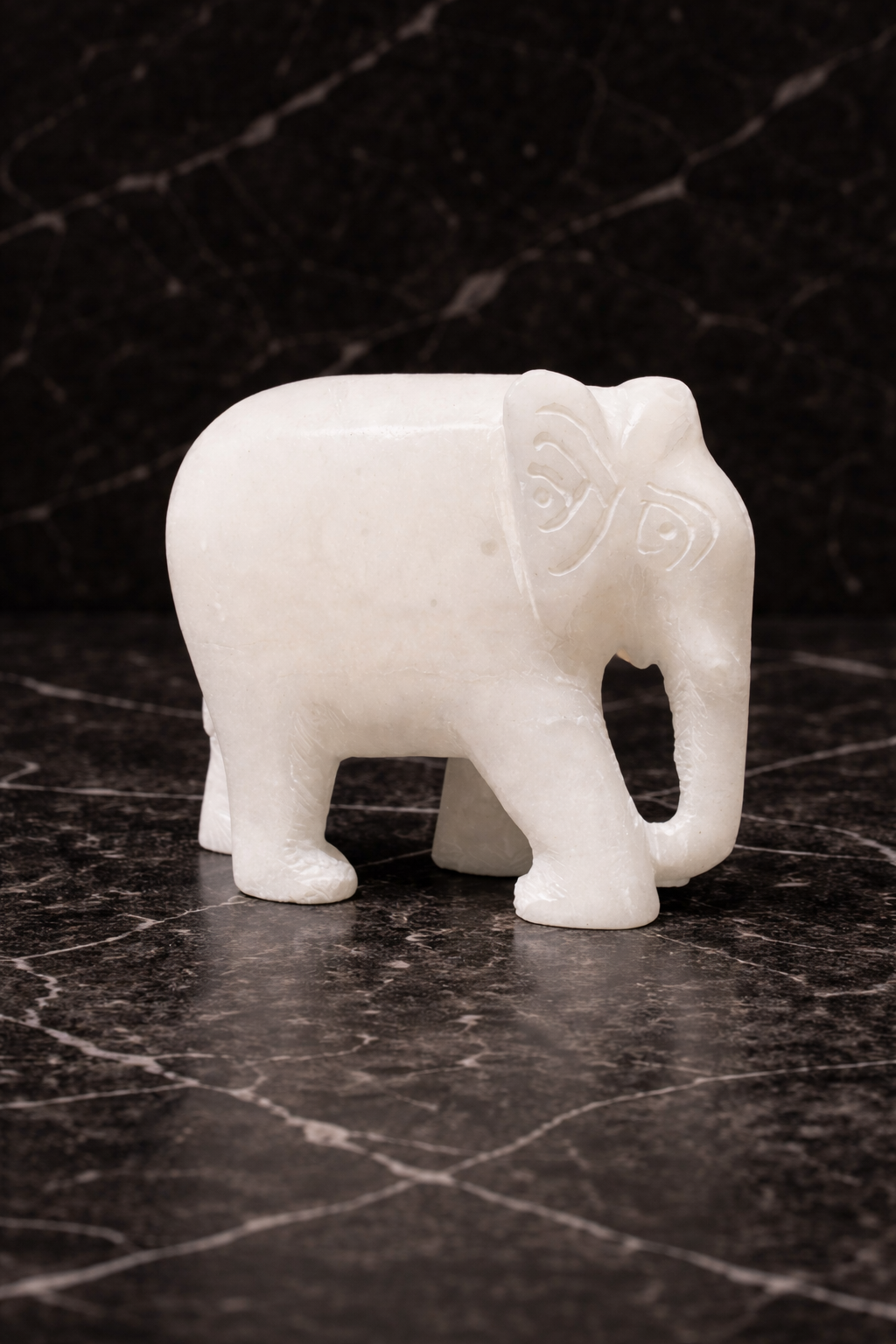 Polished white marble elephant sculpture on black marble