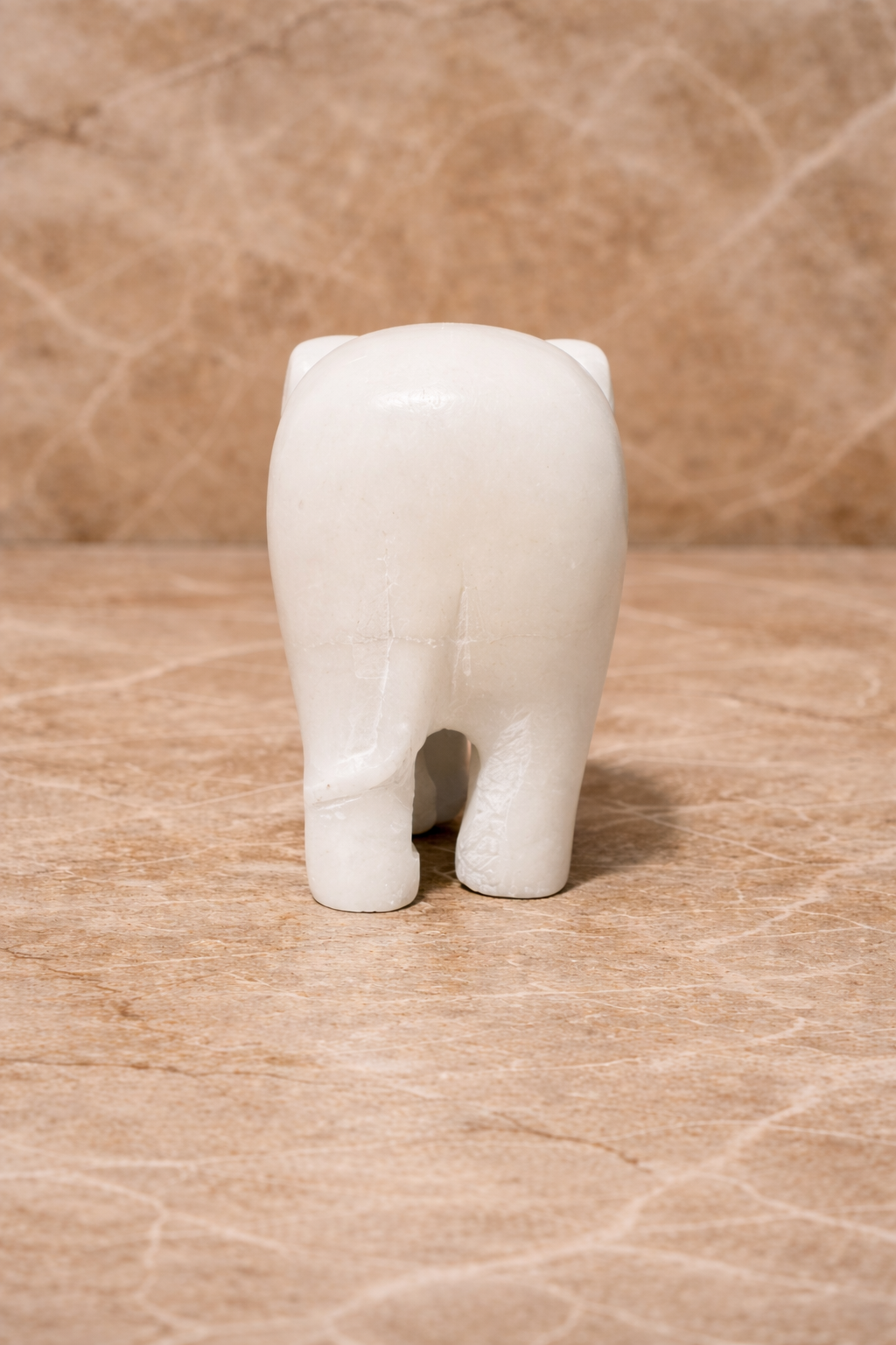 Rare Front view of polished white marble elephant sculpture on beige marble surface