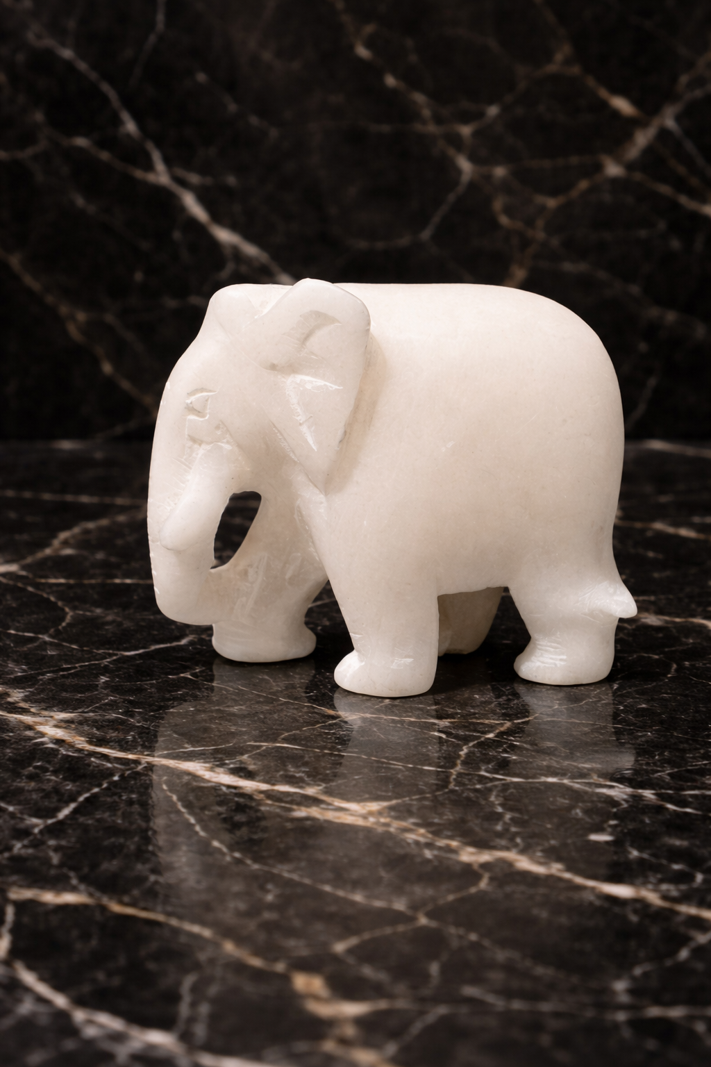 White marble elephant figurine close-up on black marble 