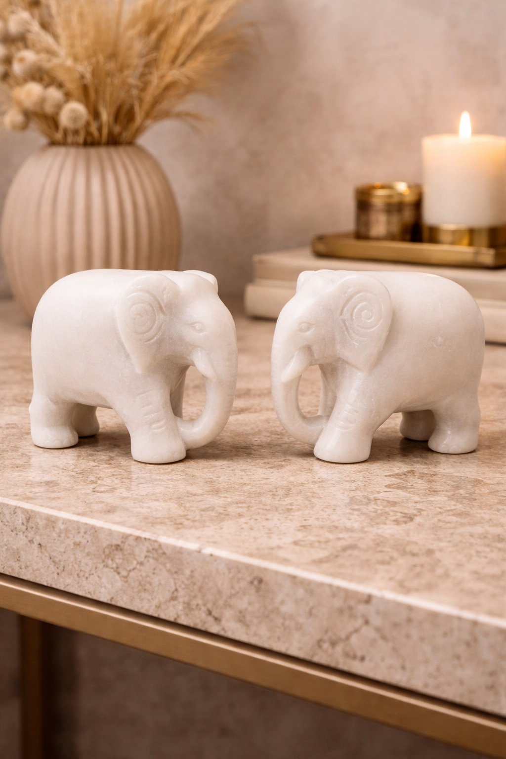 Pair of polished white marble elephant sculptures on marble table with candle and décor