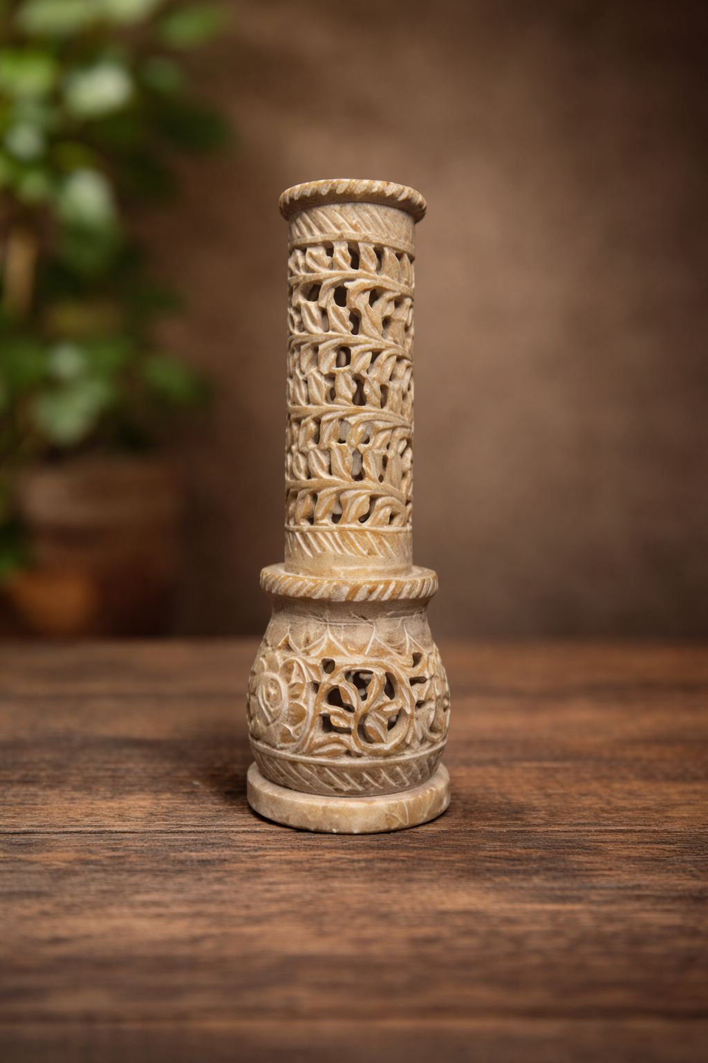 Hand-carved soapstone incense burner tower on wooden table with warm brown background