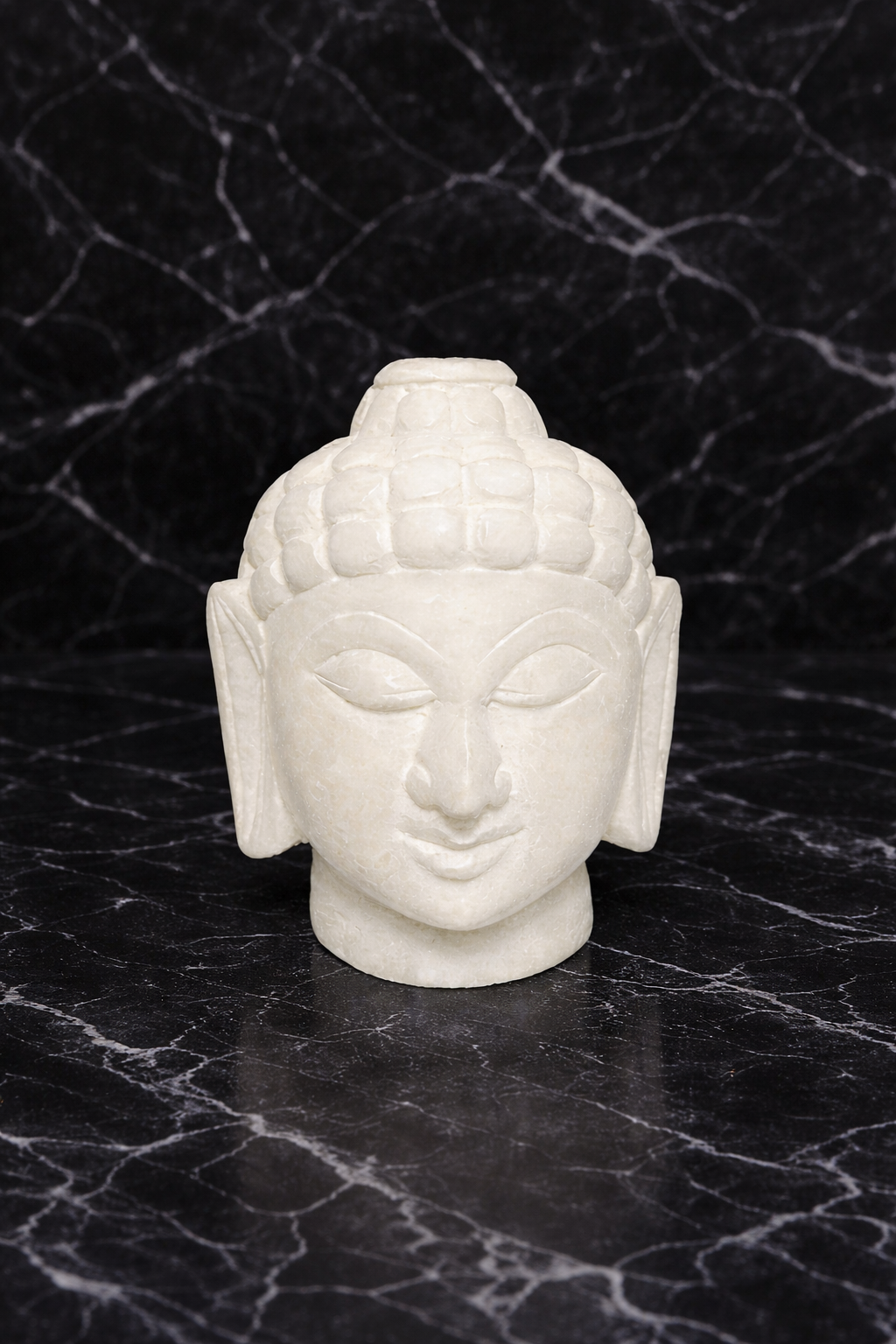 White marble Buddha head sculpture on black marble surface, minimalist zen decor