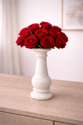 White marble vase with red roses on a wooden table