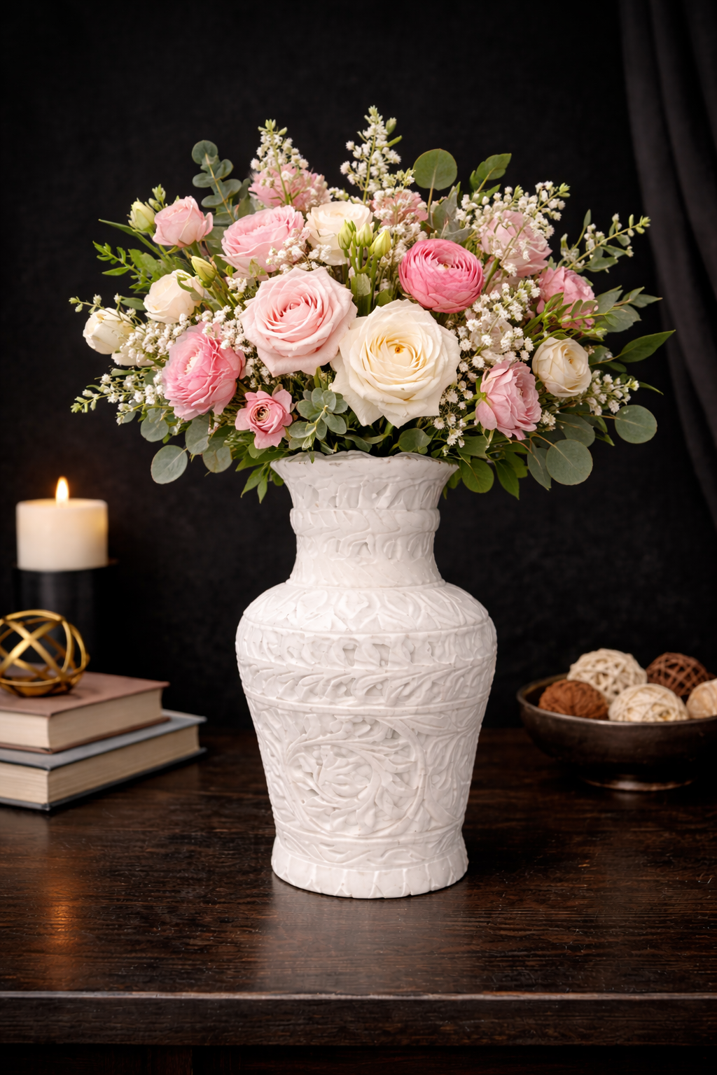 Hand-carved white marble vase with pink and white roses styled on dark wooden table with candle and decor accents