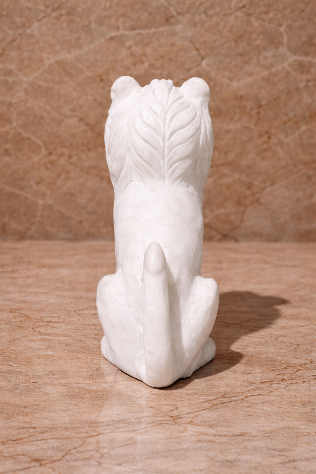 Rear view of polished white marble sitting lion sculpture on beige marble surface