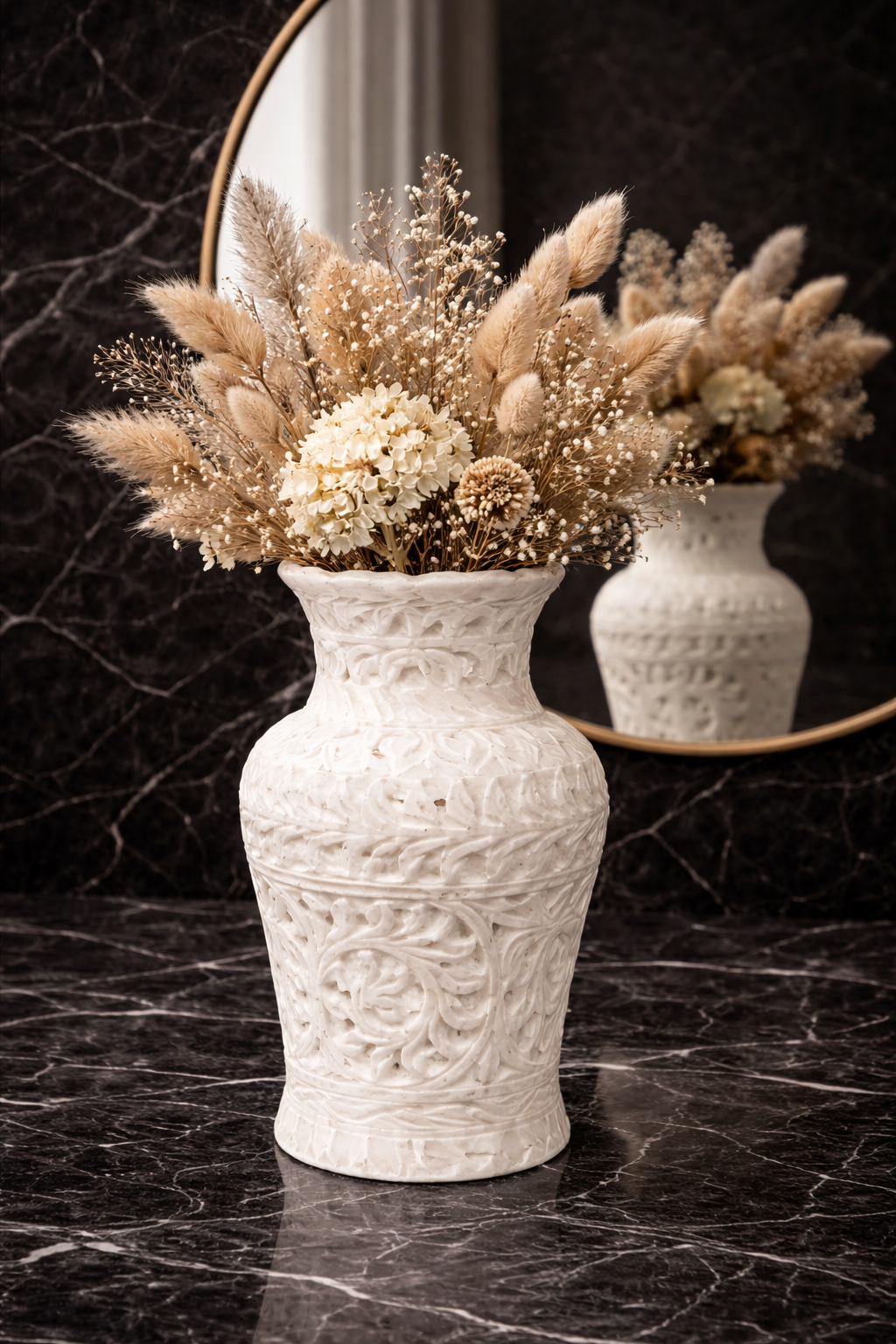 Hand-carved white marble vase with dried flowers styled as a centrepiece on a black marble coffee table in a modern living room