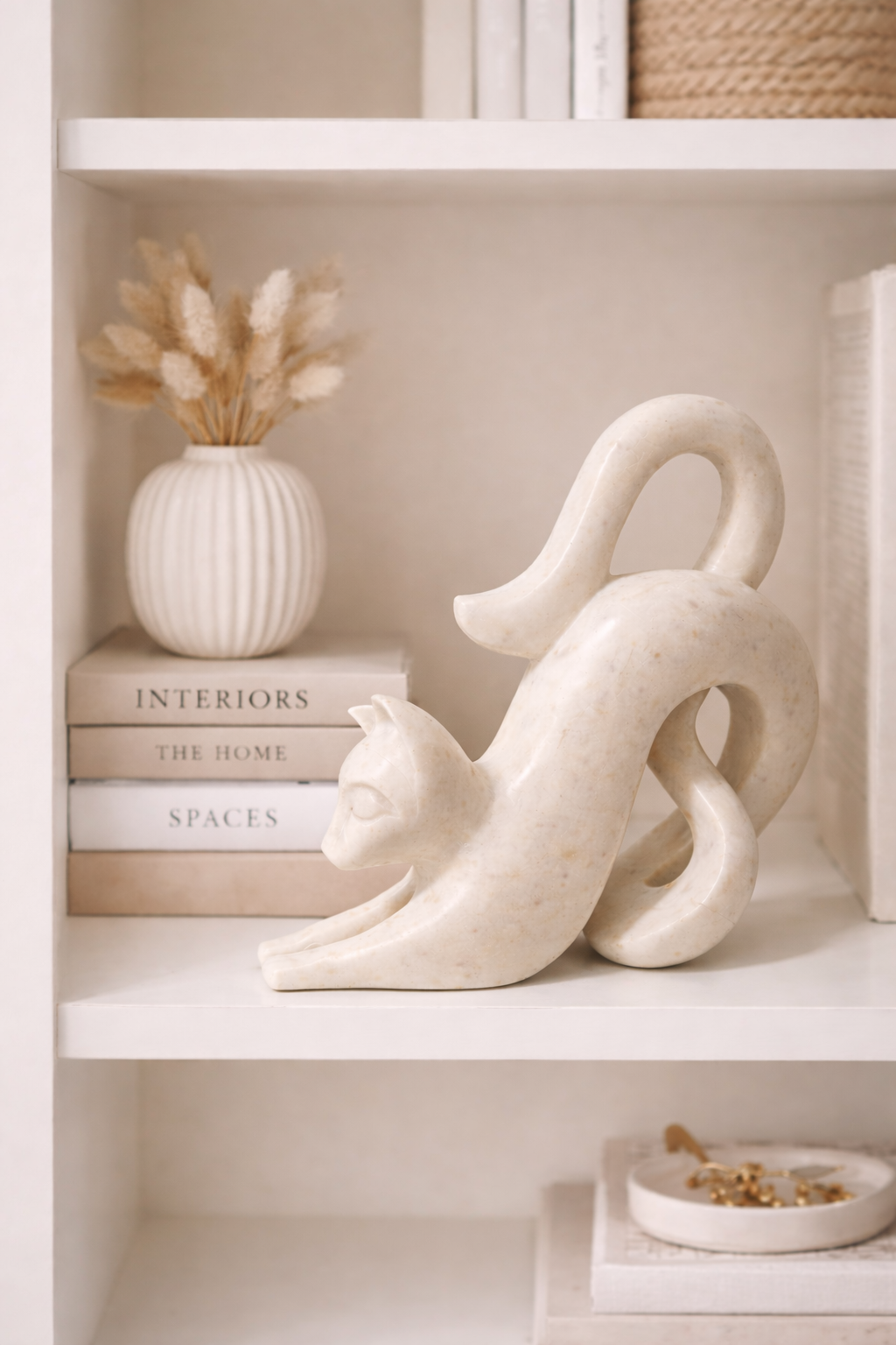 Hand-carved white marble cat sculpture styled on shelf with books and vase, luxury modern home décor NZ