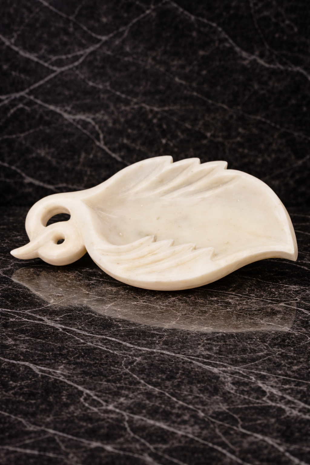 White polished marble leaf-shaped decorative bowl on dark marble surface