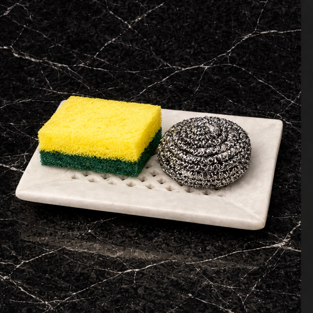 Perforated marble tray used as kitchen sponge holder beside sink, functional stone kitchen accessory NZ.