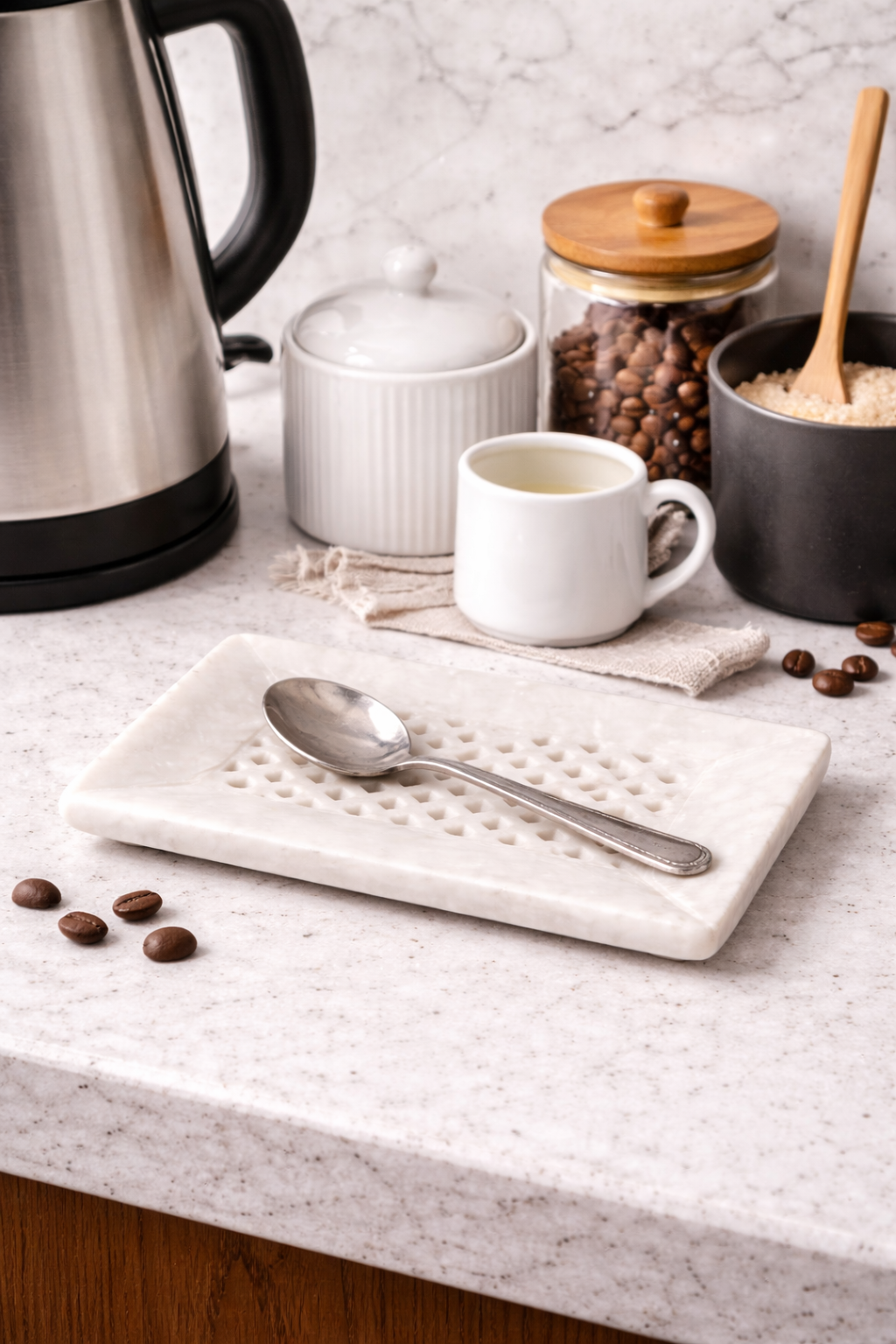 Perforated white marble tray used as spoon rest on kitchen coffee station countertop, luxury stone decor NZ.