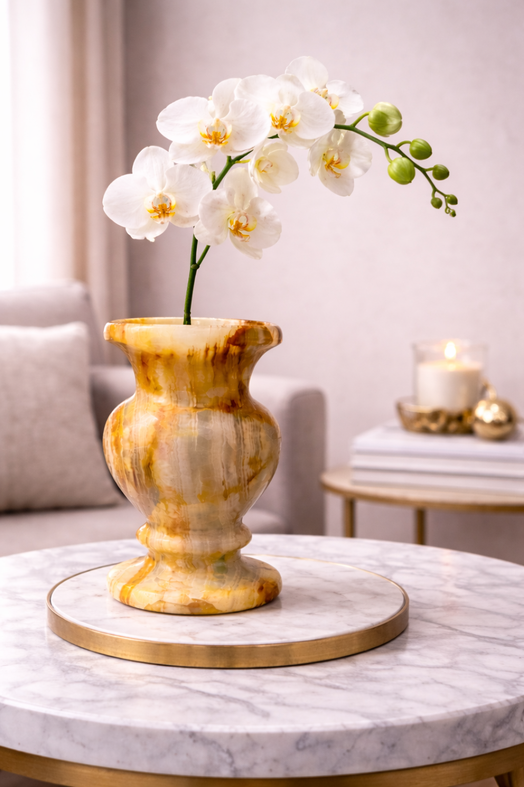 White orchid in an onyx vase on a marble table with a candle in the background