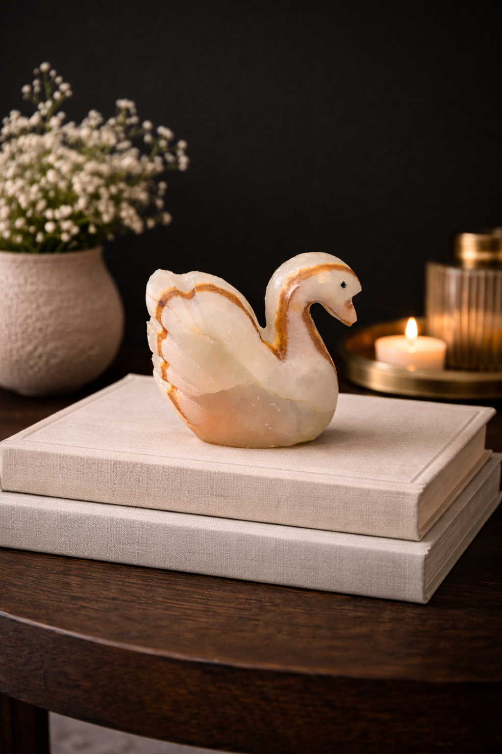 Polished natural onyx swan figurine displayed on stacked books as decor accent