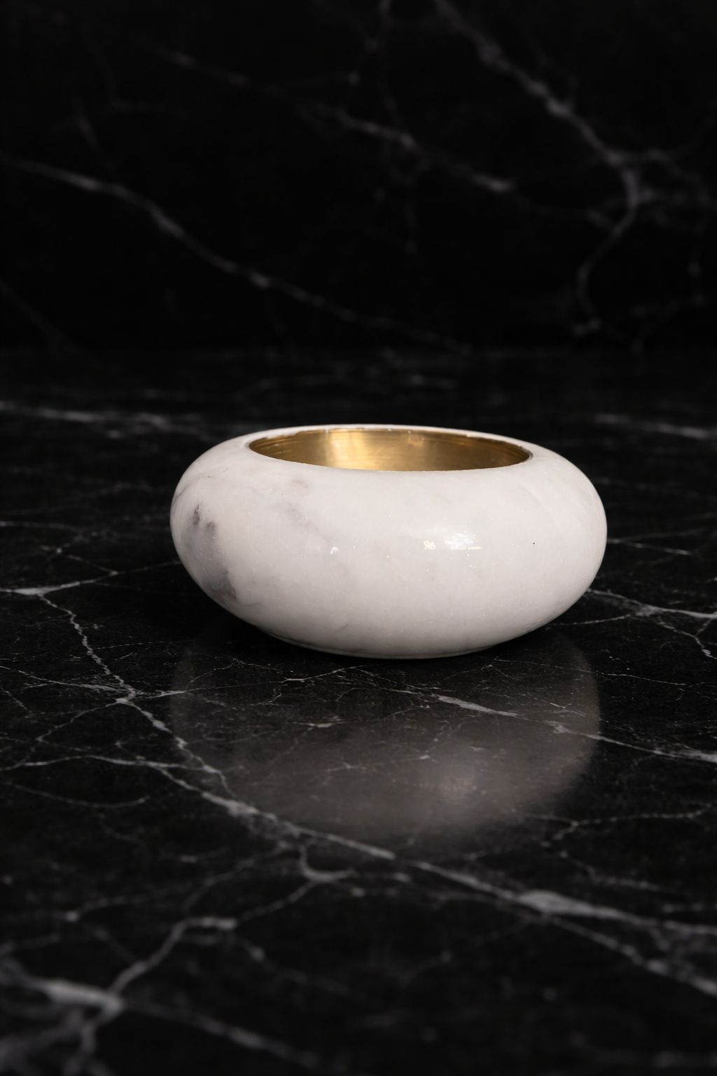 Minimalist round marble candle holder with brass cup on black marble surface, elegant décor NZ