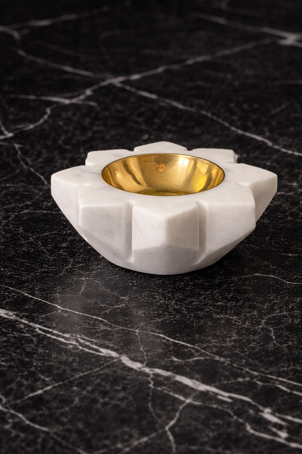 Decorative white holder with a gold interior on a black marble surface