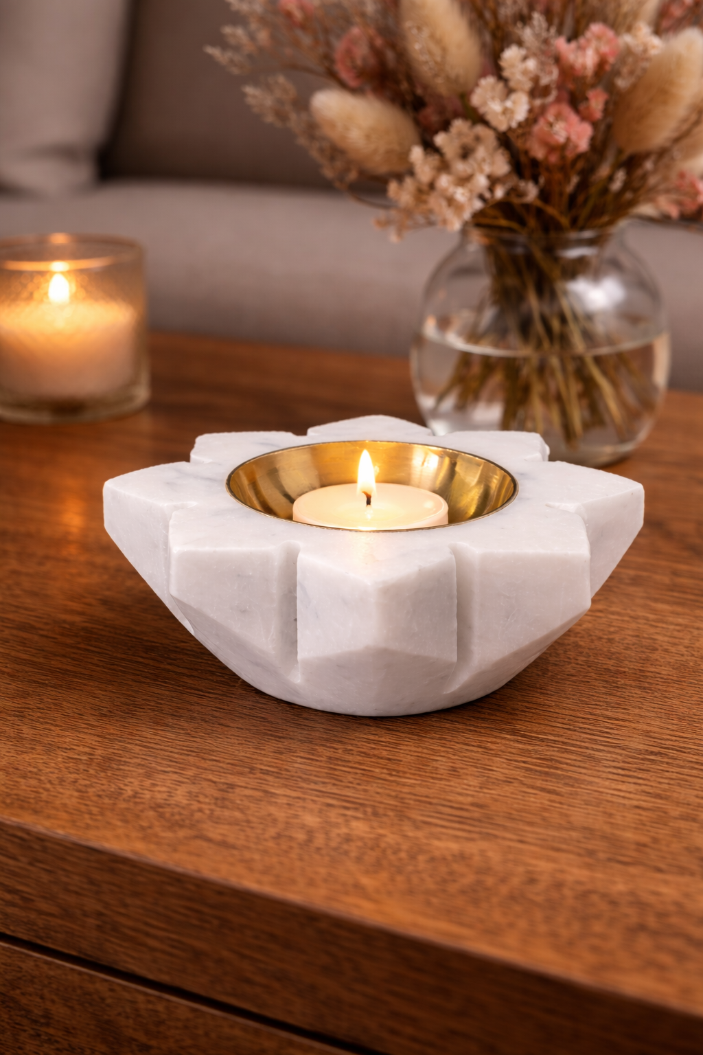 Hand-crafted white marble lotus tealight holder with brass insert and lit candle on wooden table, luxury home décor NZ