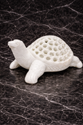 Hand-carved white marble turtle sculpture with lattice shell design on black marble background
