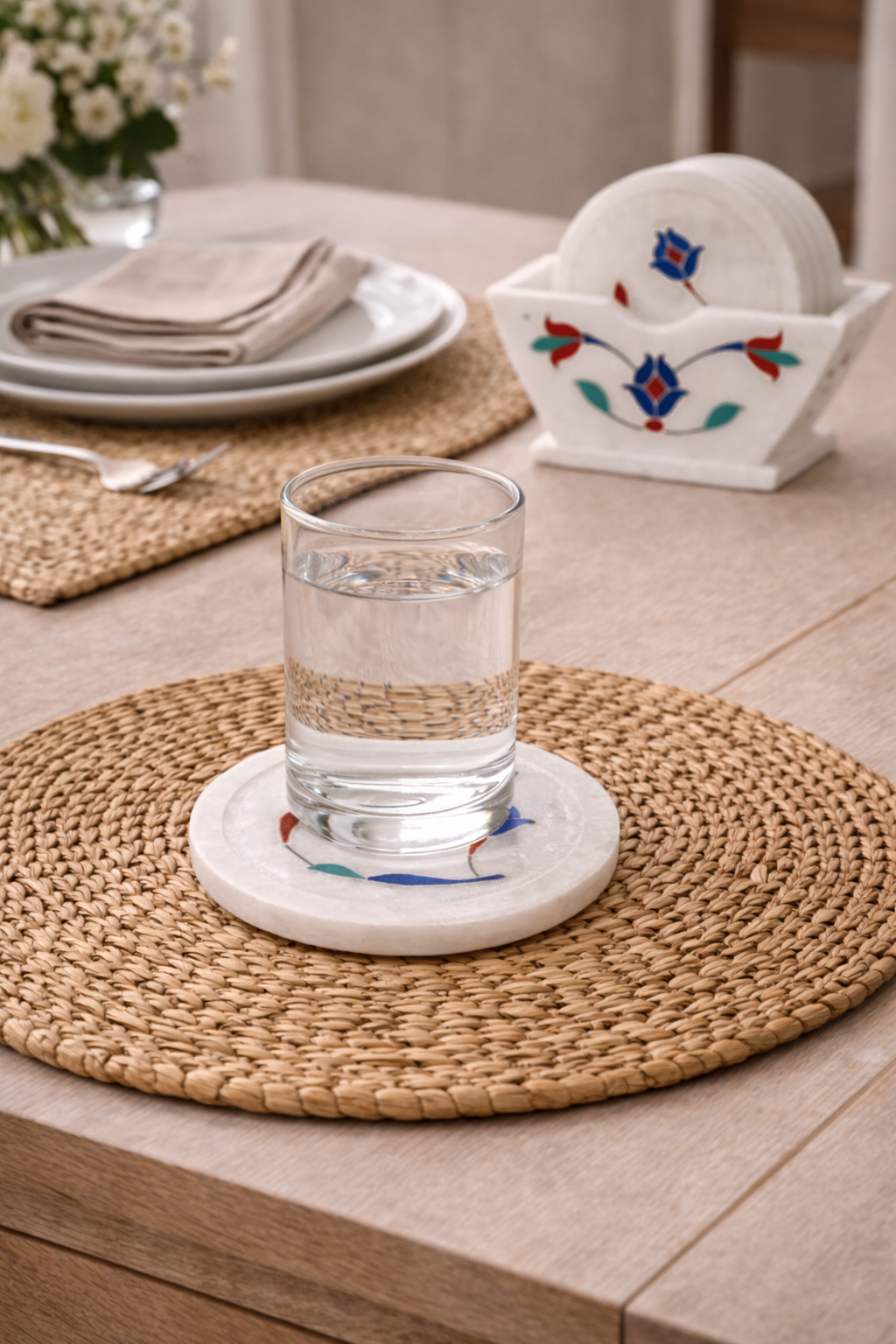 Luxury white marble coaster with colourful floral stone inlay holding water glass