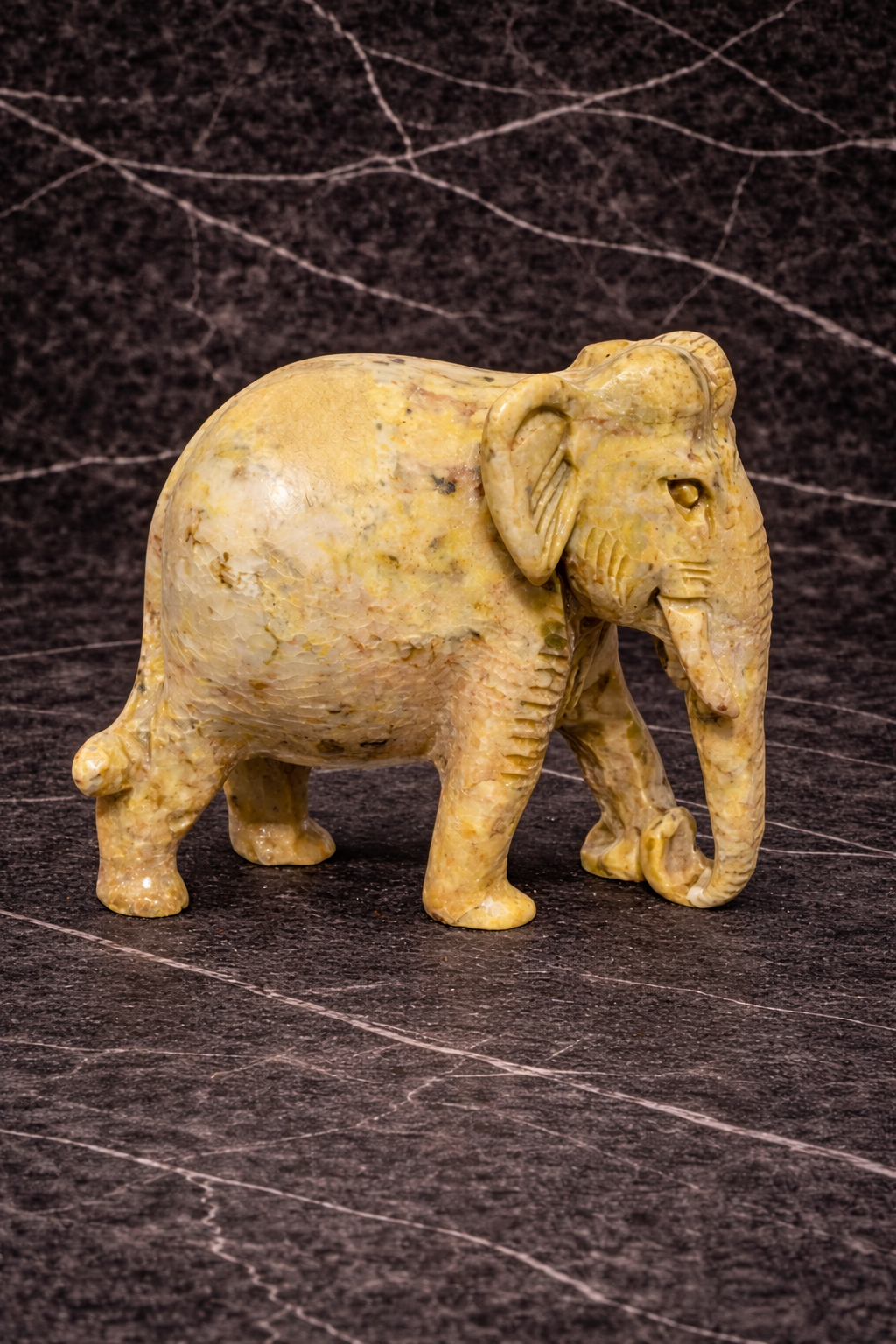 Natural stone elephant sculpture used as decorative home accent on a dark marble surface